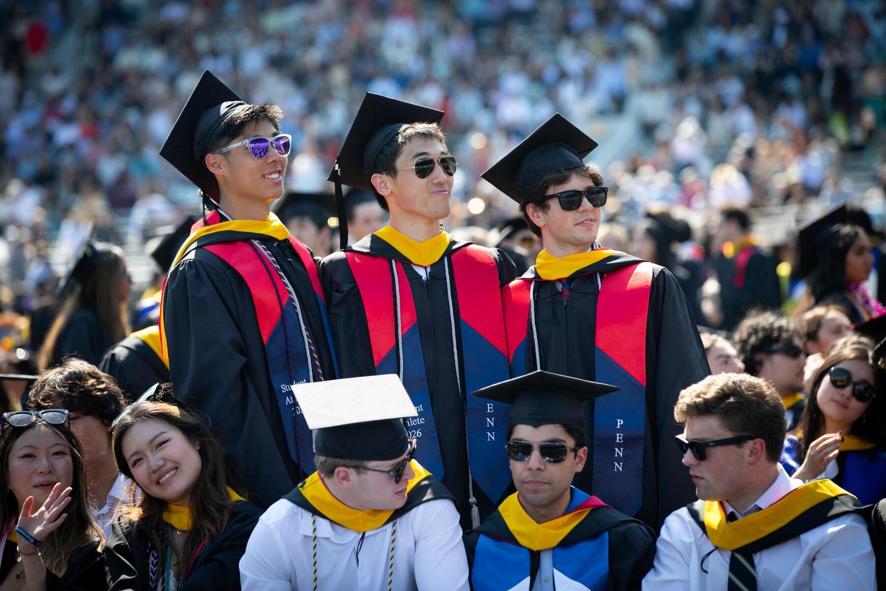 Three graduates standing on franklin field during the commencement ceremony.