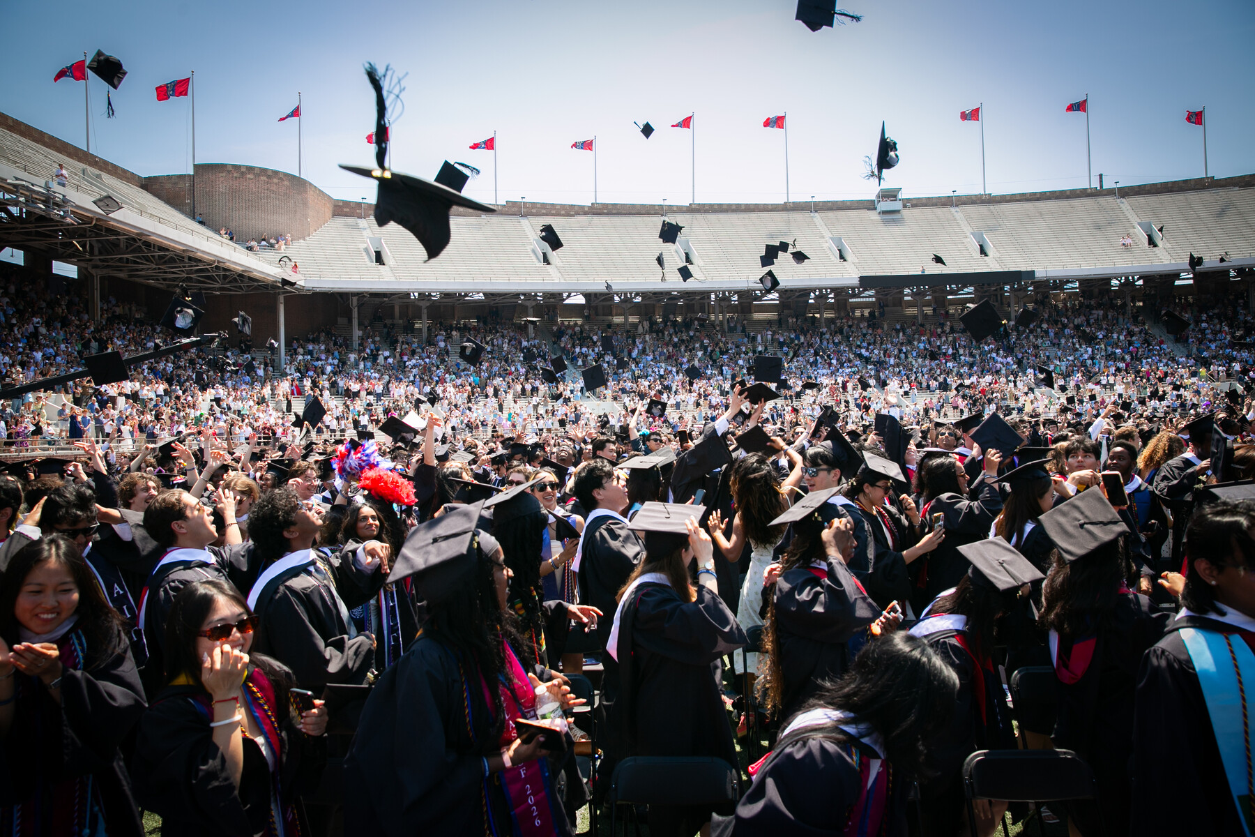 Penn graduates throwing their graduation caps in the air on Franklin Field during Commencement.