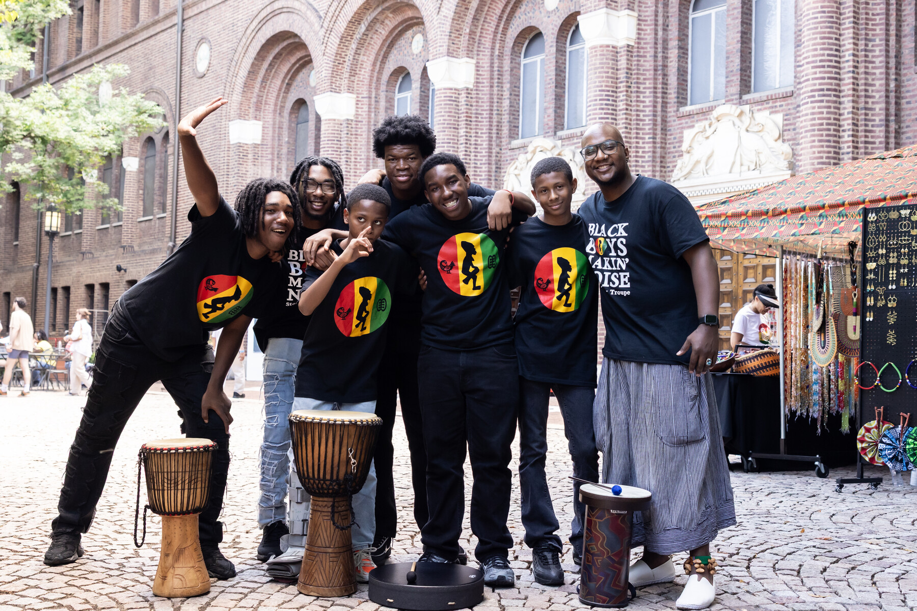 A group of performers posing for a group shot with drums outside the Penn museum.