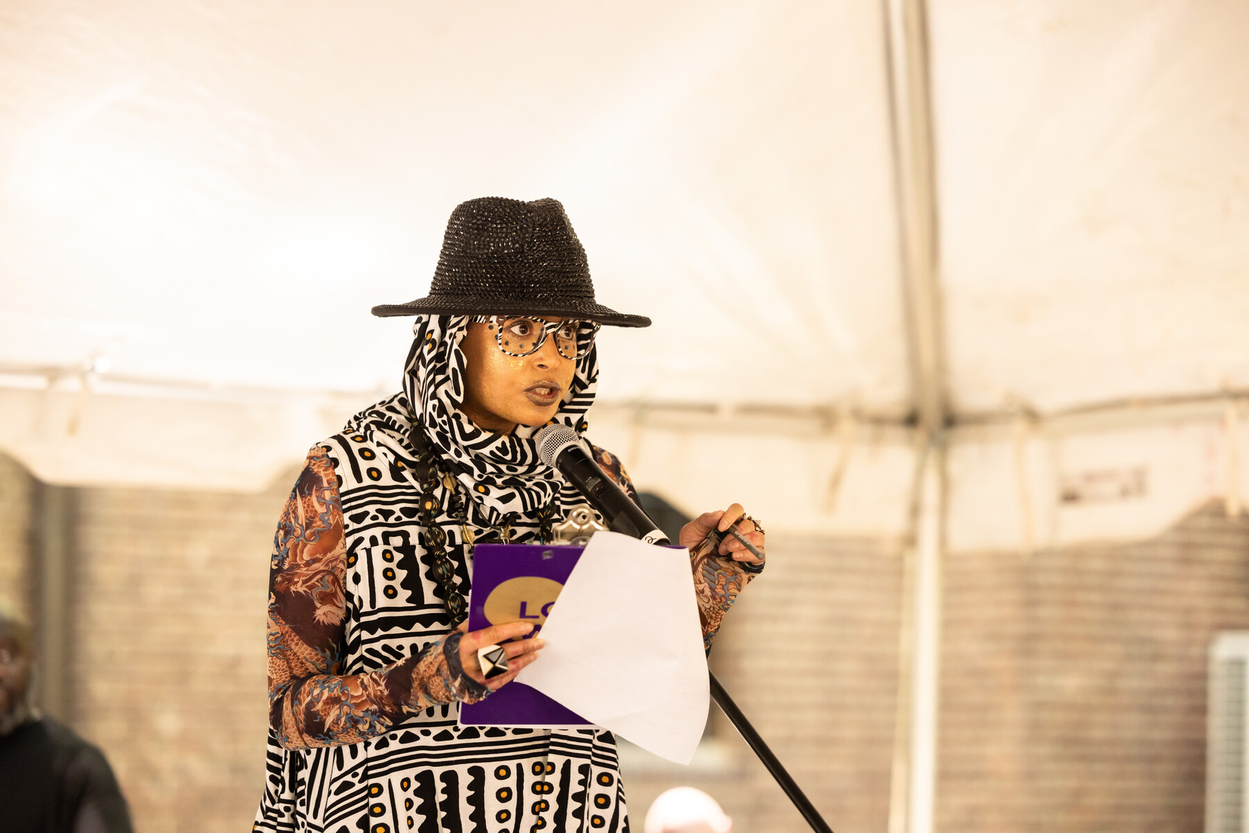 A speaker speaking into a microphone at the Penn Museum Juneteenth celebration.