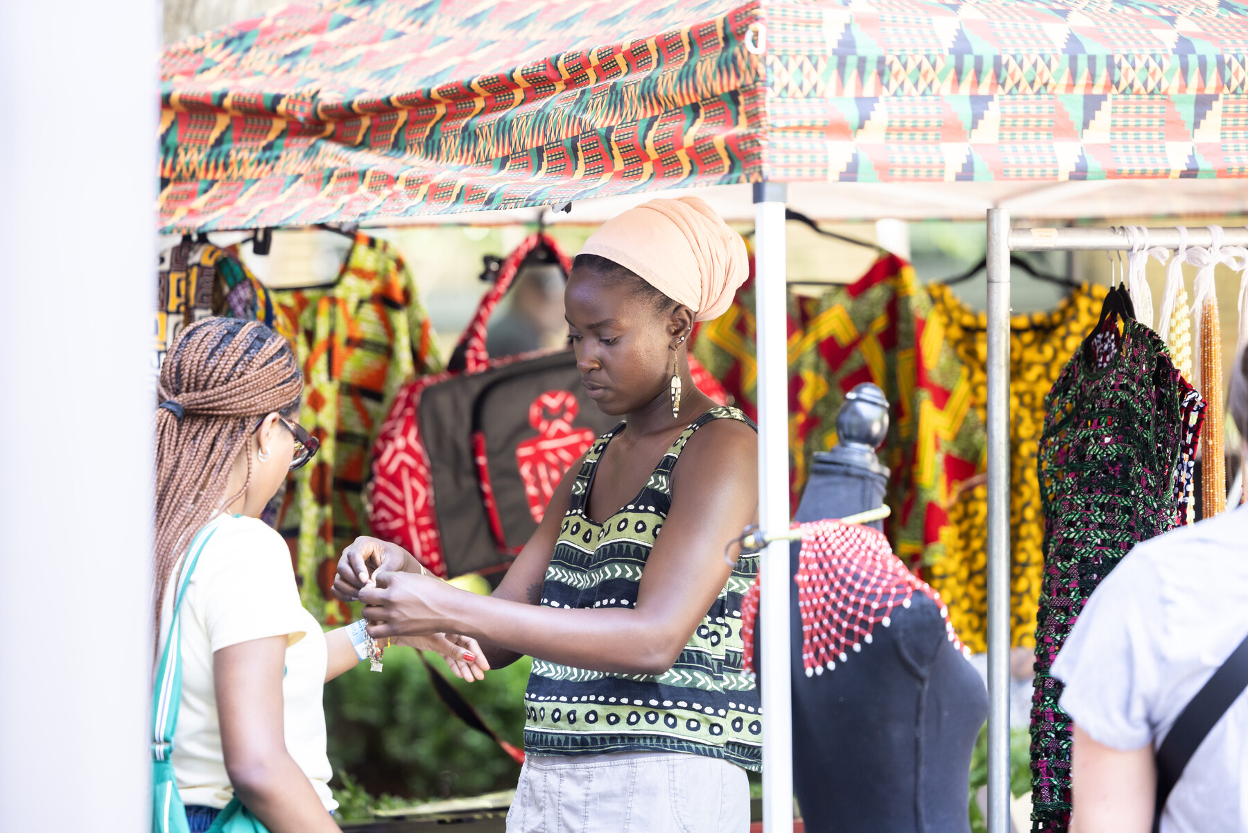 A vendor tying a bracelet onto someone’s arm at a booth.