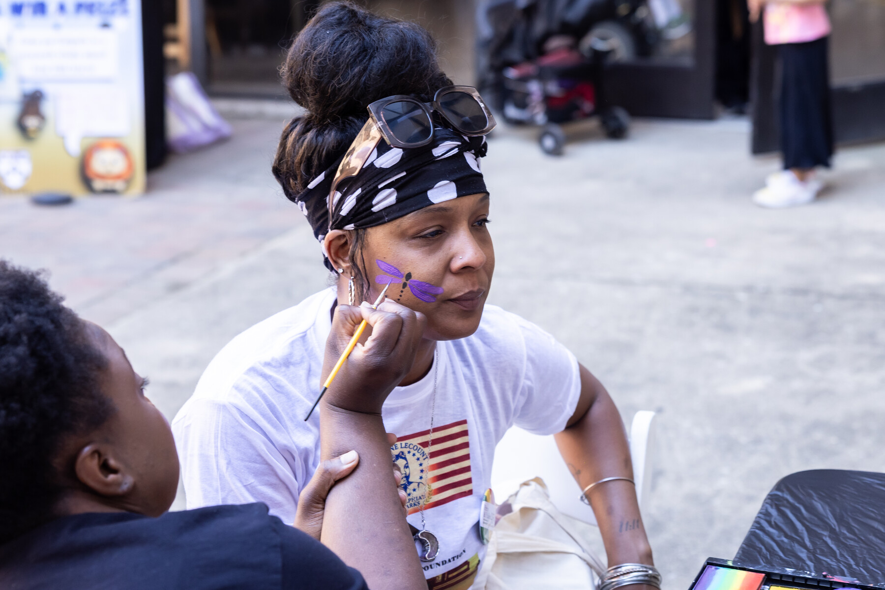 A person having a firefly painted on their cheek.