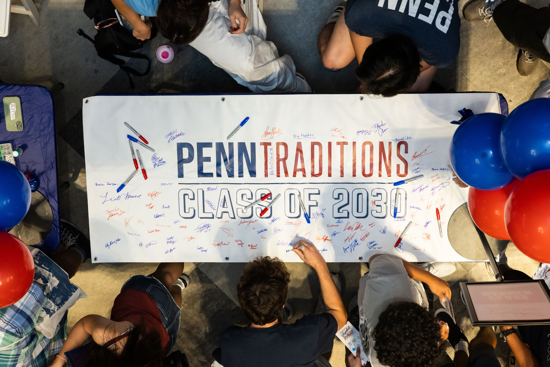Students signing a large Penn Traditions Class of 2030 banner.