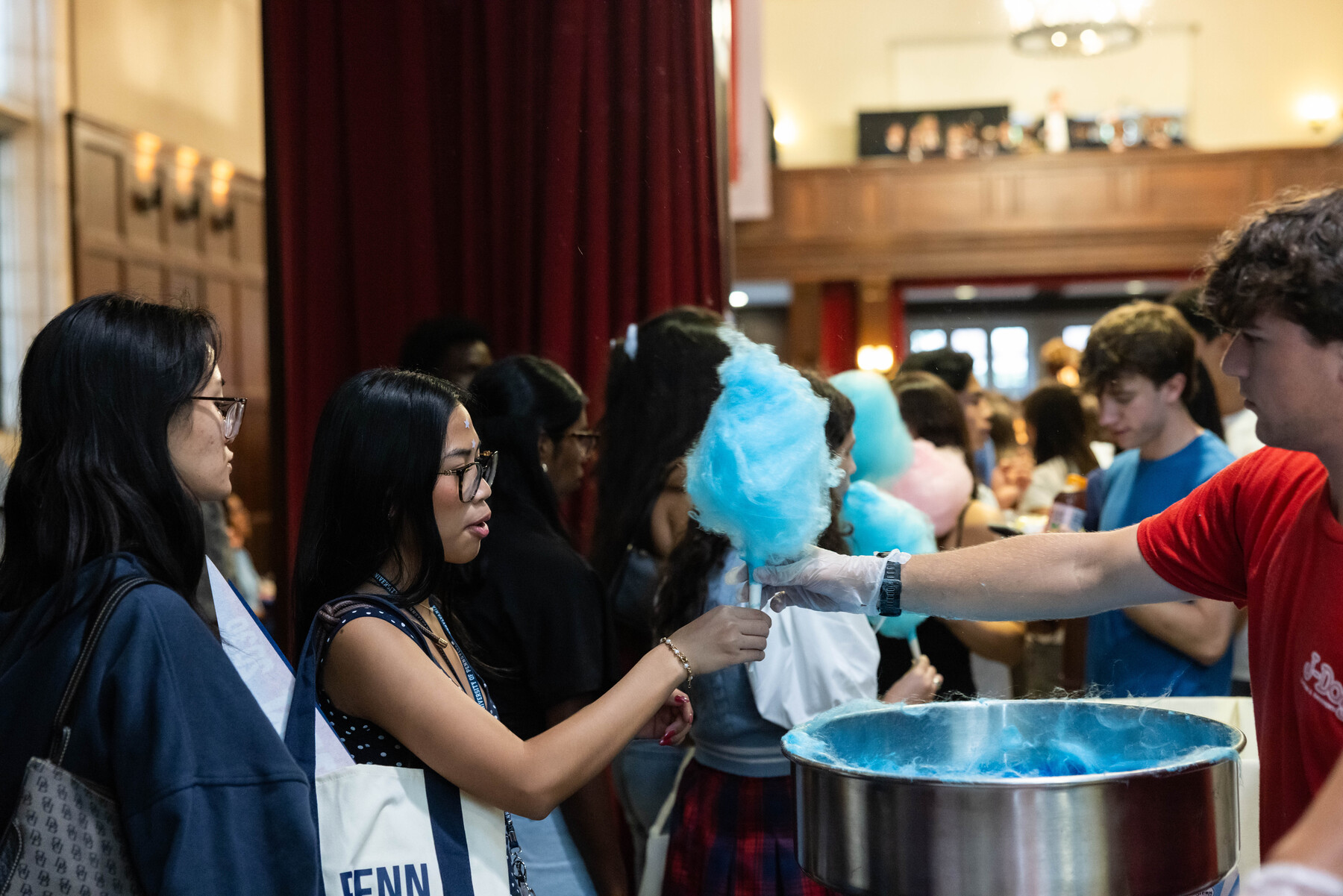 A Penn student handing another student a blue cotton candy stick.