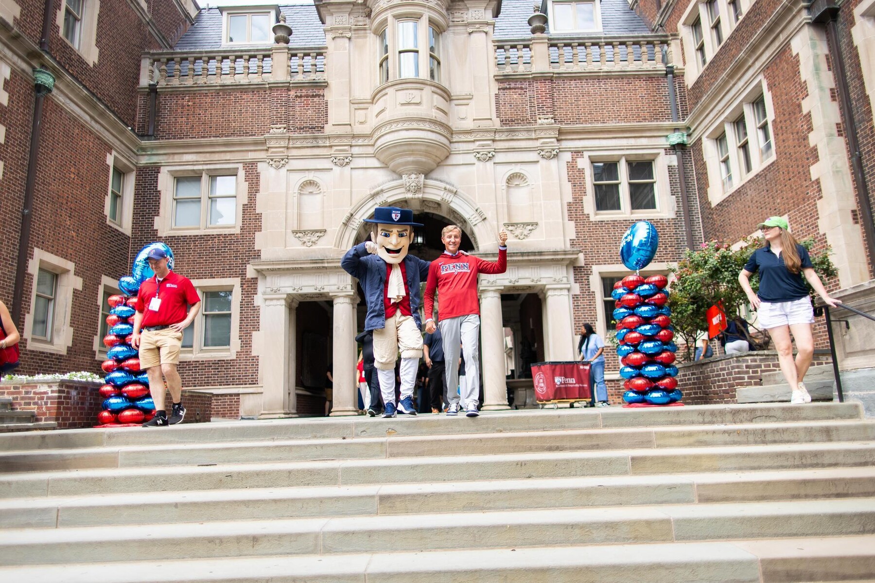 J. Larry Jameson and the Quaker walking down the stairs outside the Quad during Move-In.