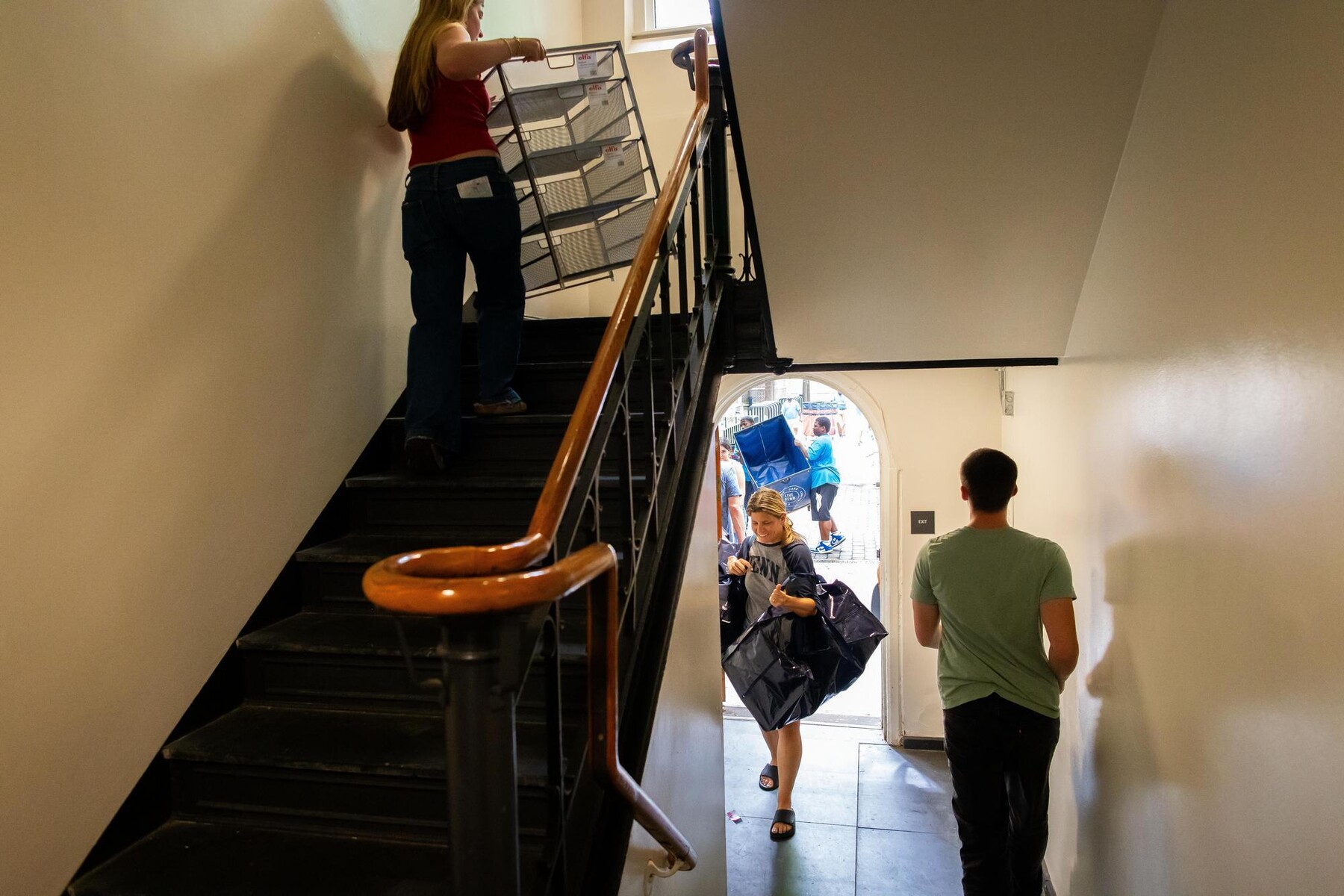 Students walking into a dorm and up the stairs with belongings during Move-In.