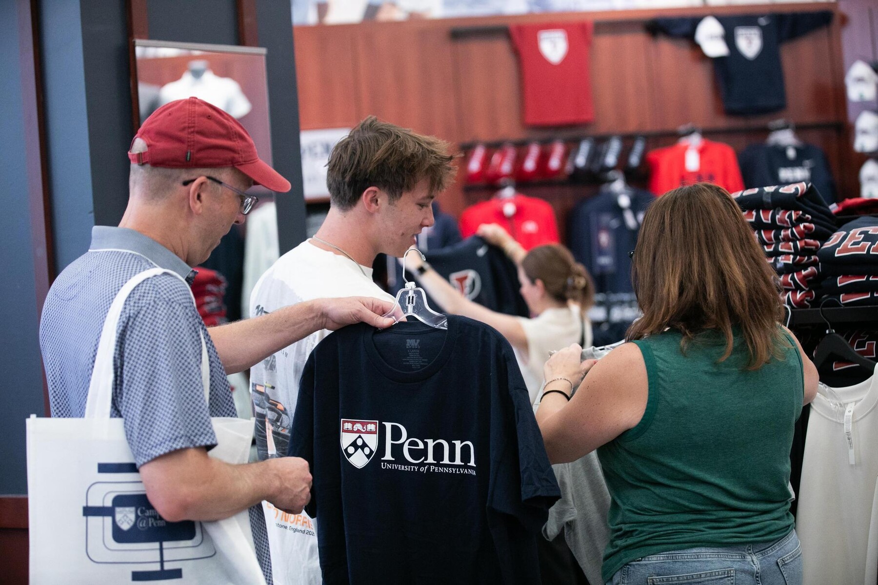A student and their parent choosing Penn shirts from the penn bookstore. 