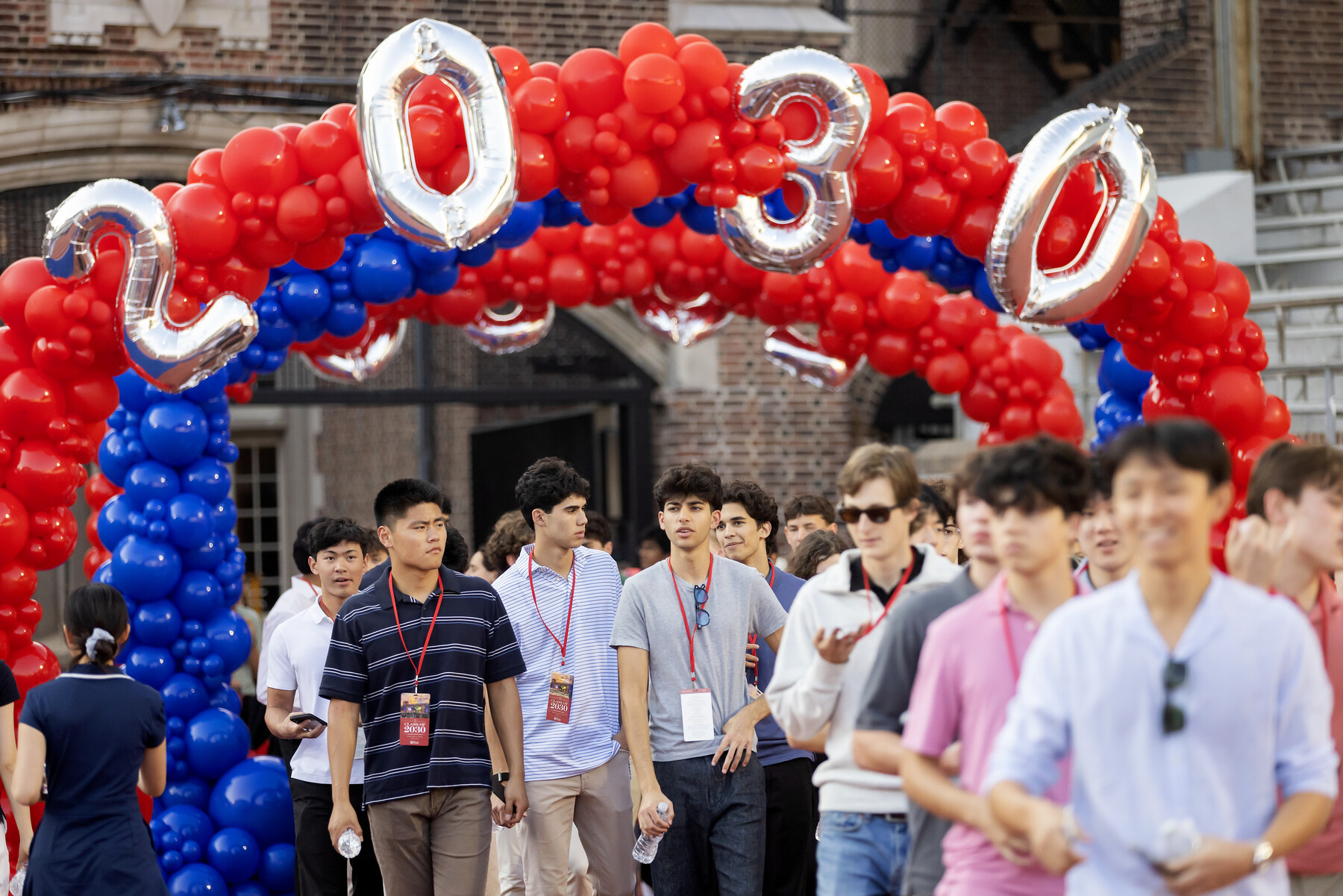 The Class of 2030 walking under a balloon arch onto Franklin Field.