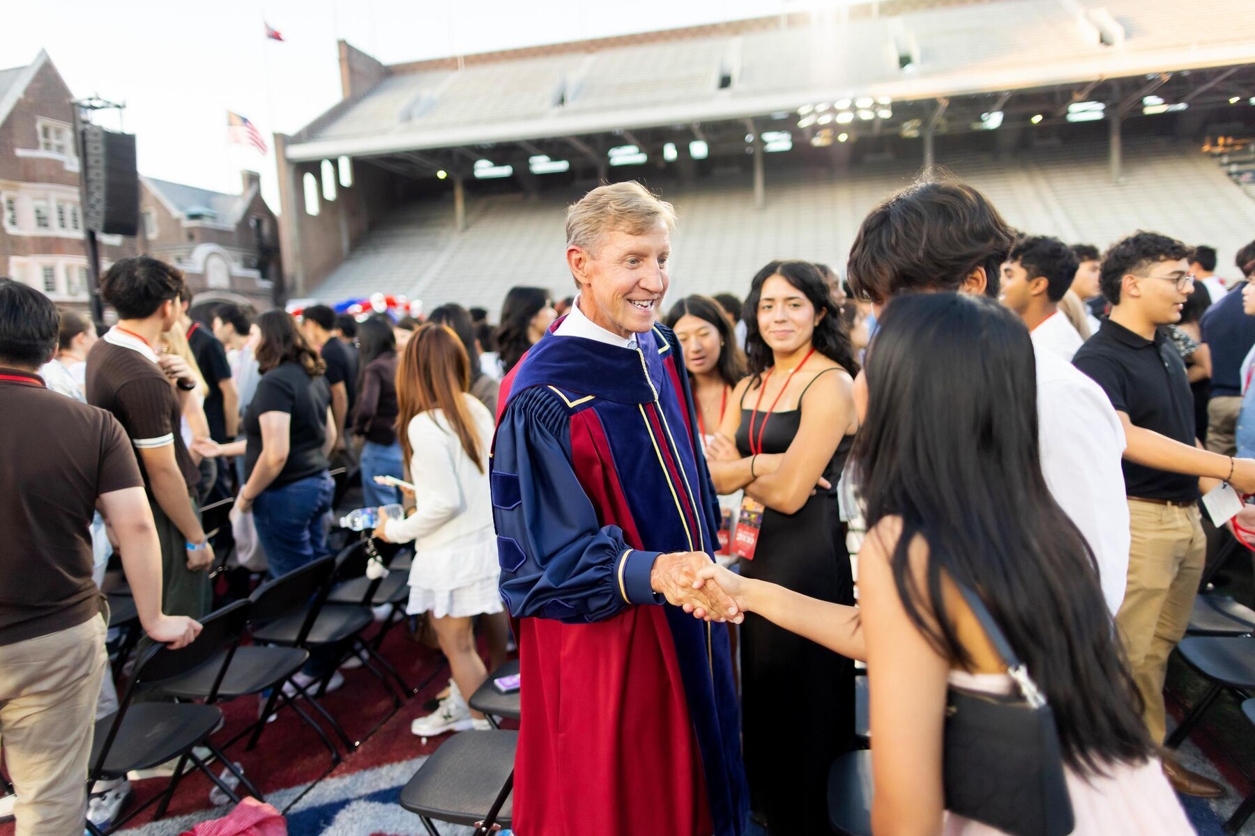 Penn President J. Larry Jameson shaking hands with a Class of 2030 undergrad on Franklin Field.