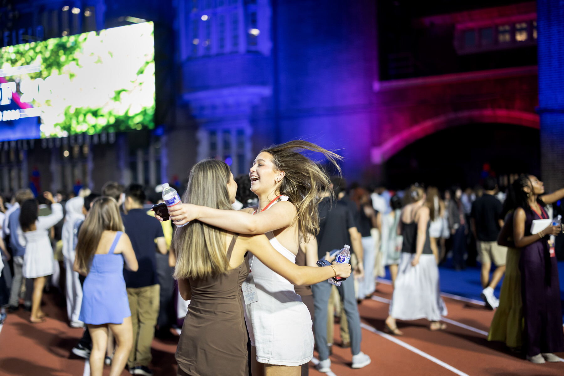 Two Class of 2030 undergrads hugging on Franklin Field after Convocation.