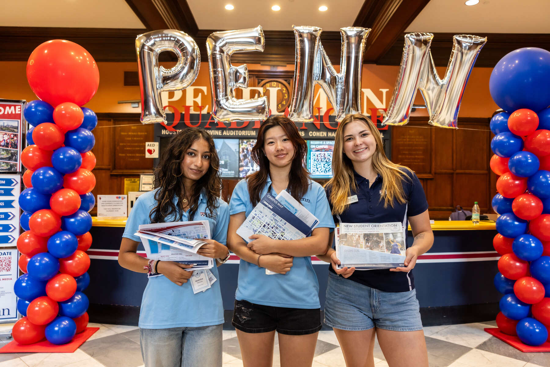 Three penn students in Houston Hall under a Penn balloon arch.