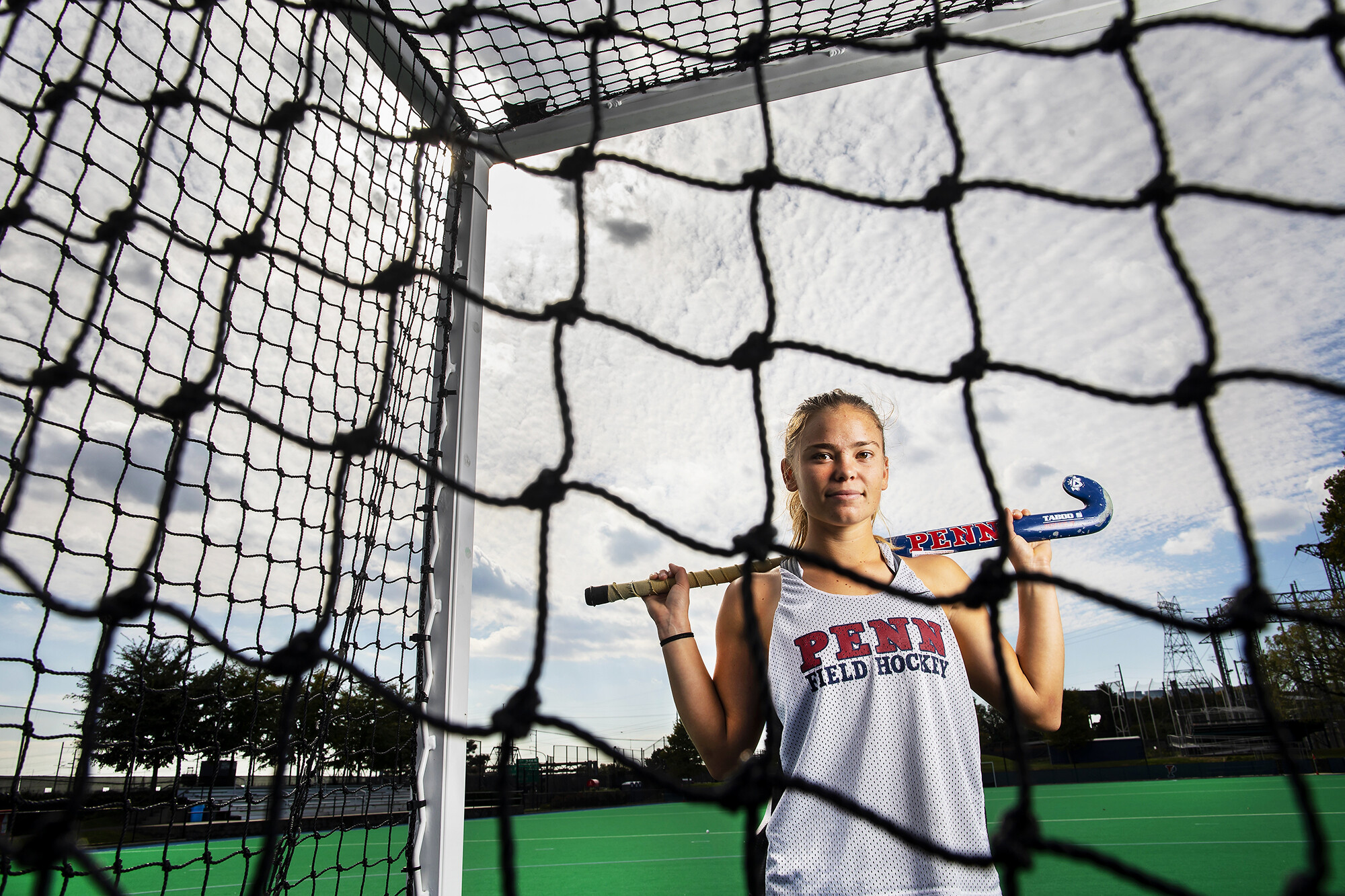 Schneck poses through a field hockey net