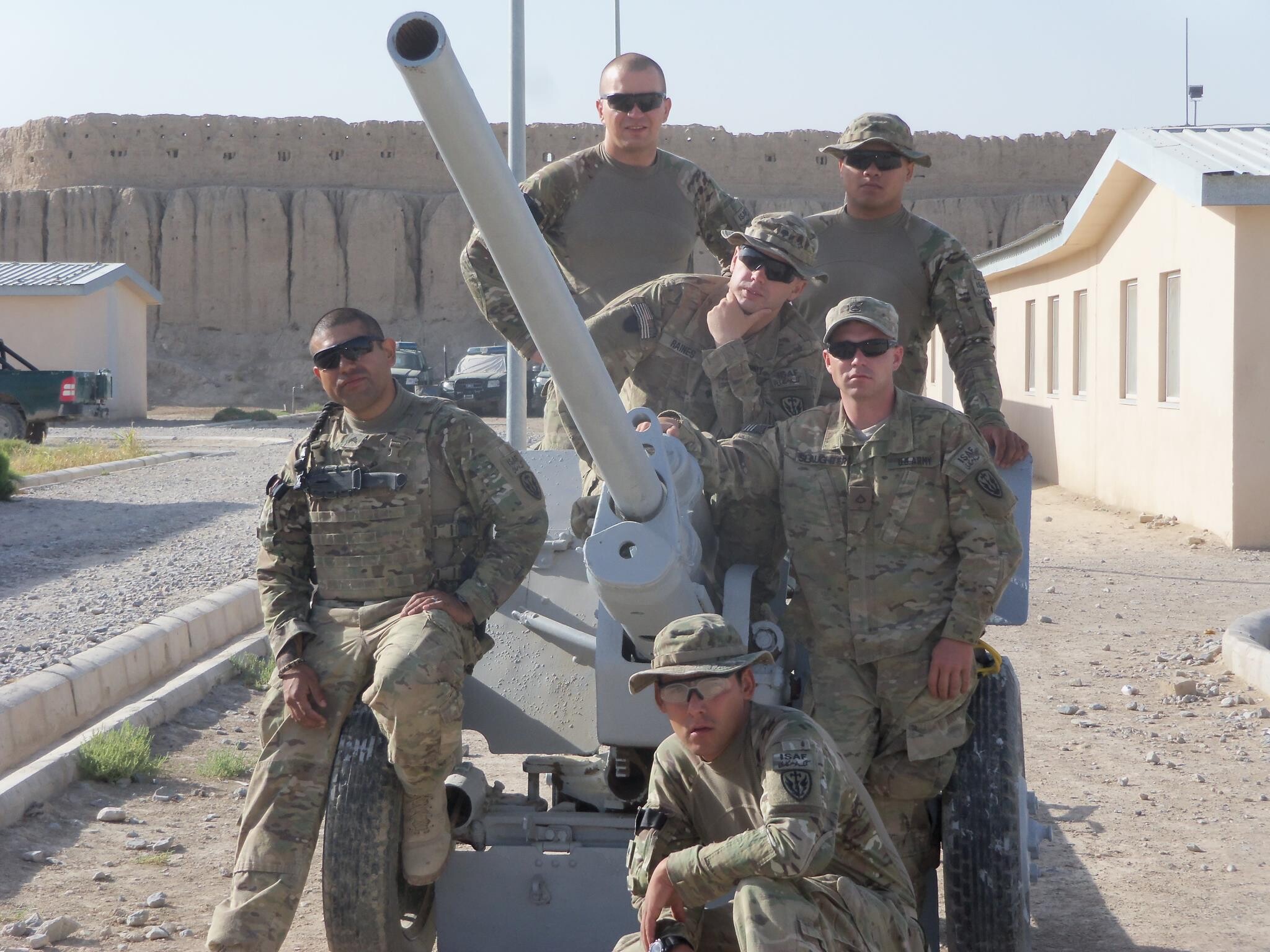 Jesse Raines in camouflage military uniform, surrounded by members of his squadron in Afghanistan