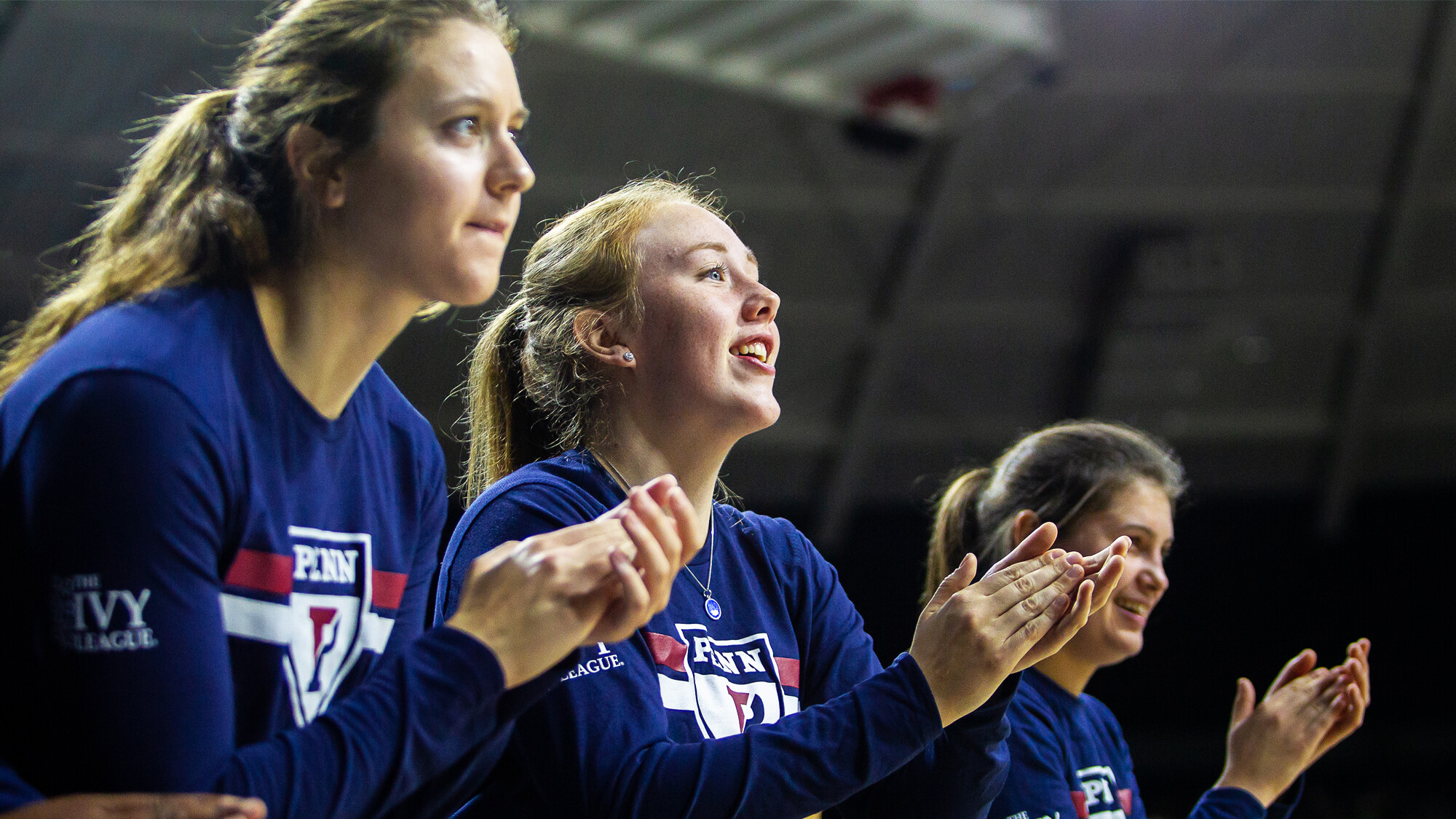 Women's basketball players cheer on their teammates from the bench.