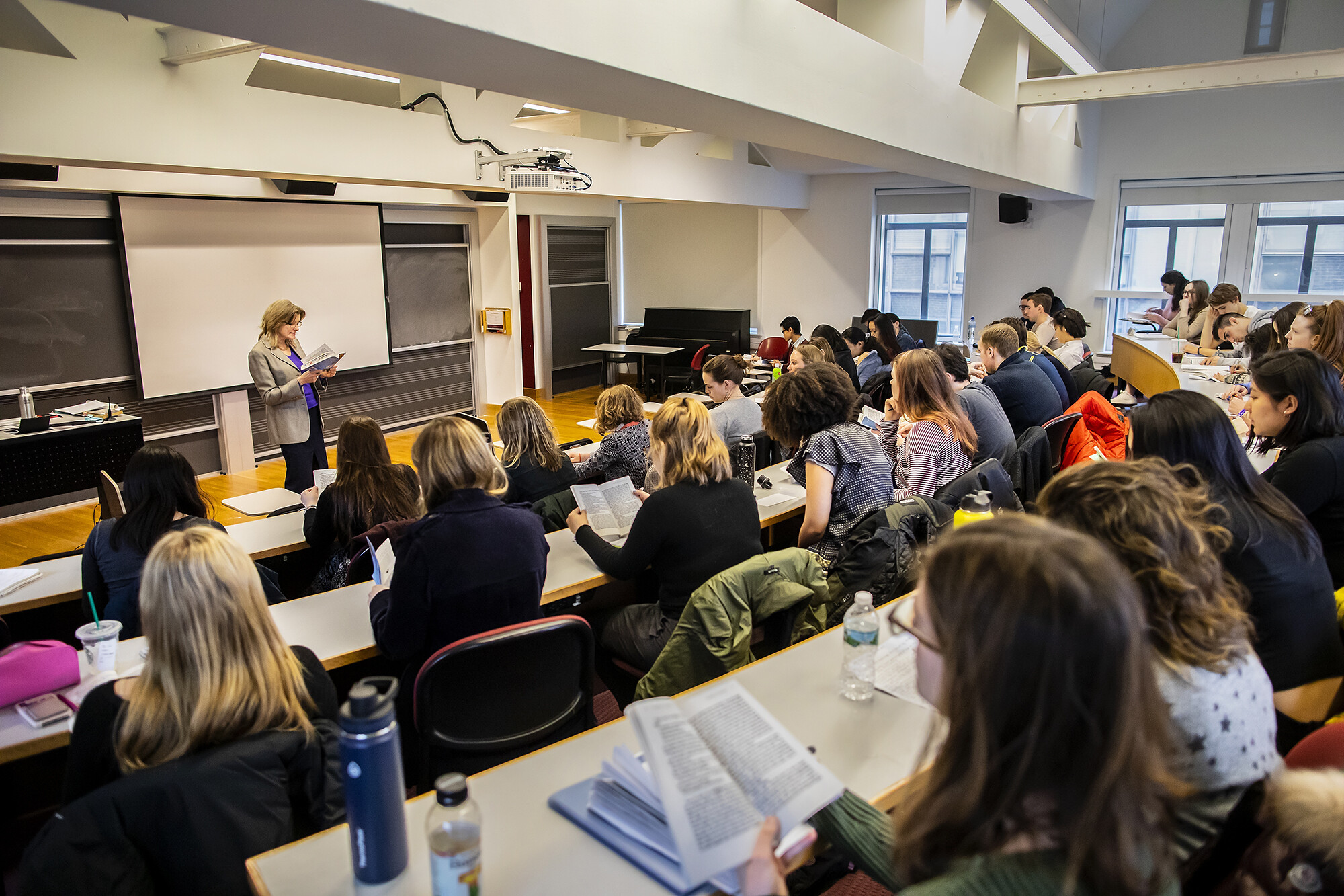 Jennifer Egan speaking in front of full classroom looking at a book. 