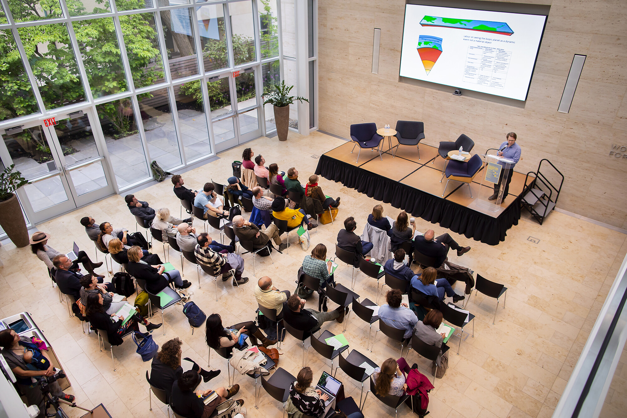 Aerial view of audience viewing speaker on stage with presentation