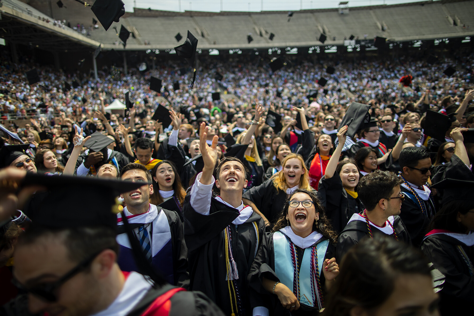 Graduating students toss their caps in the air.