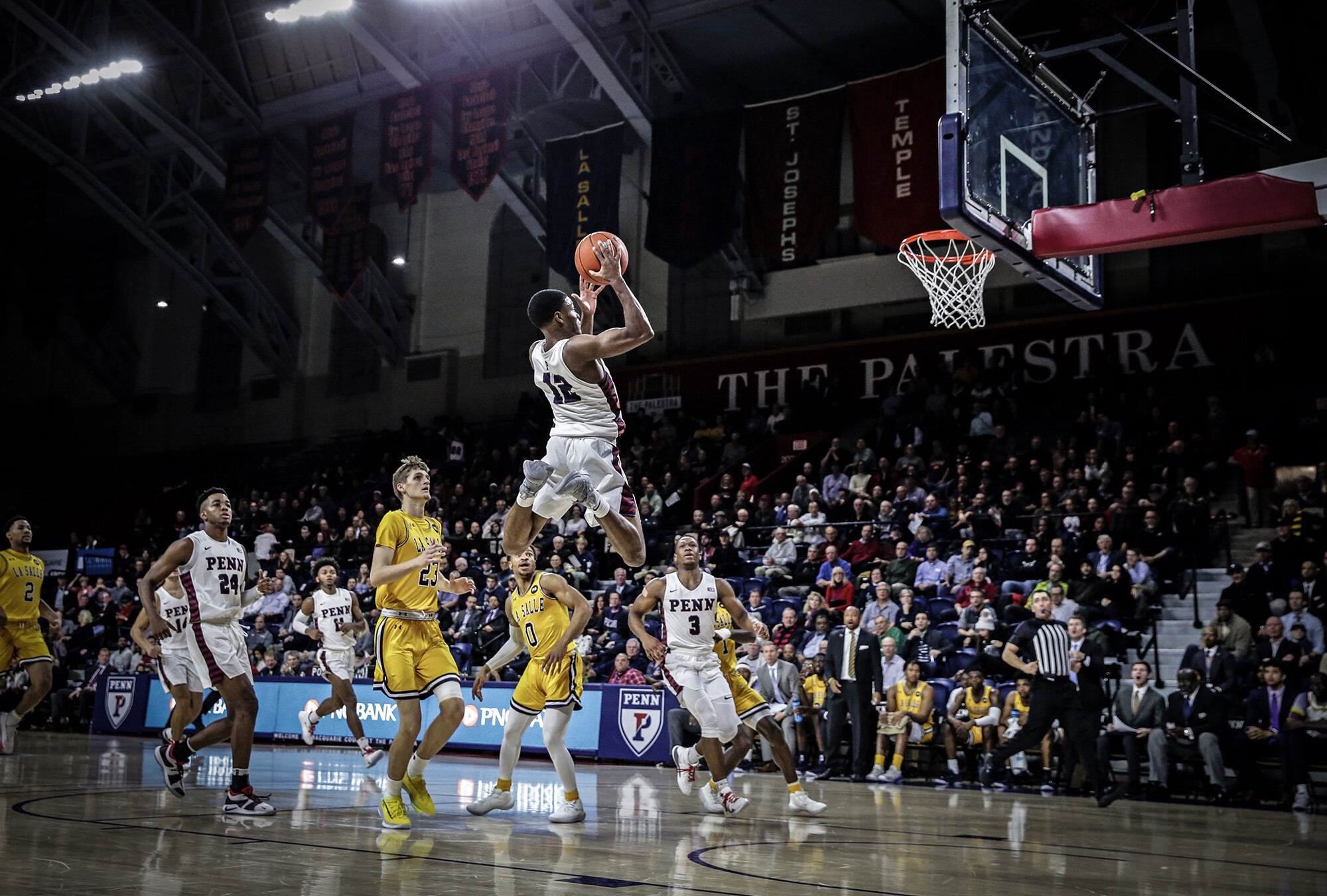 Devon Goodman of the men's basketball team hangs in the air near the basket with the ball at the Palestra.