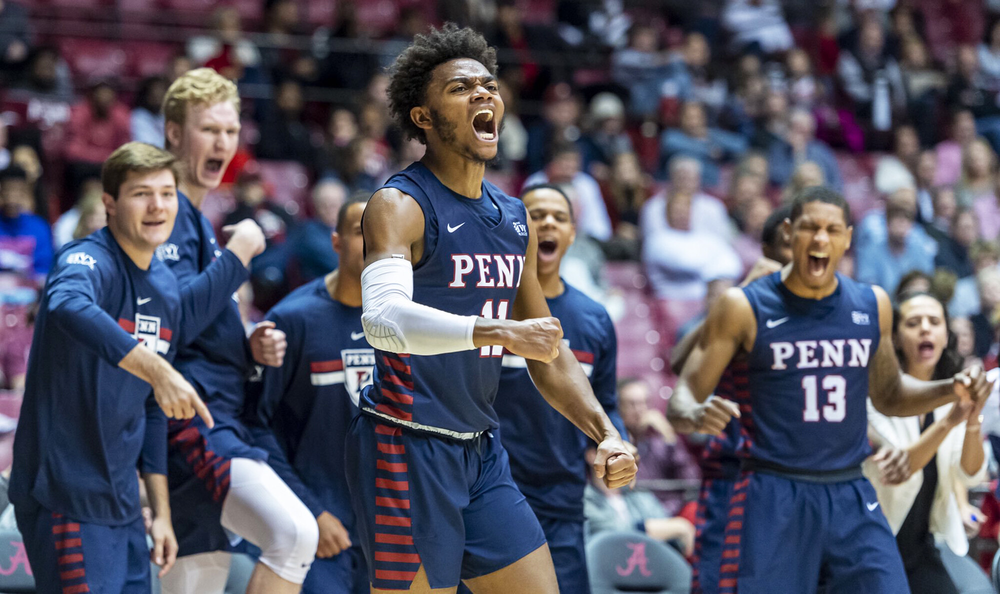 Members of the basketball team cheer on their teammates from the bench against Alabama.
