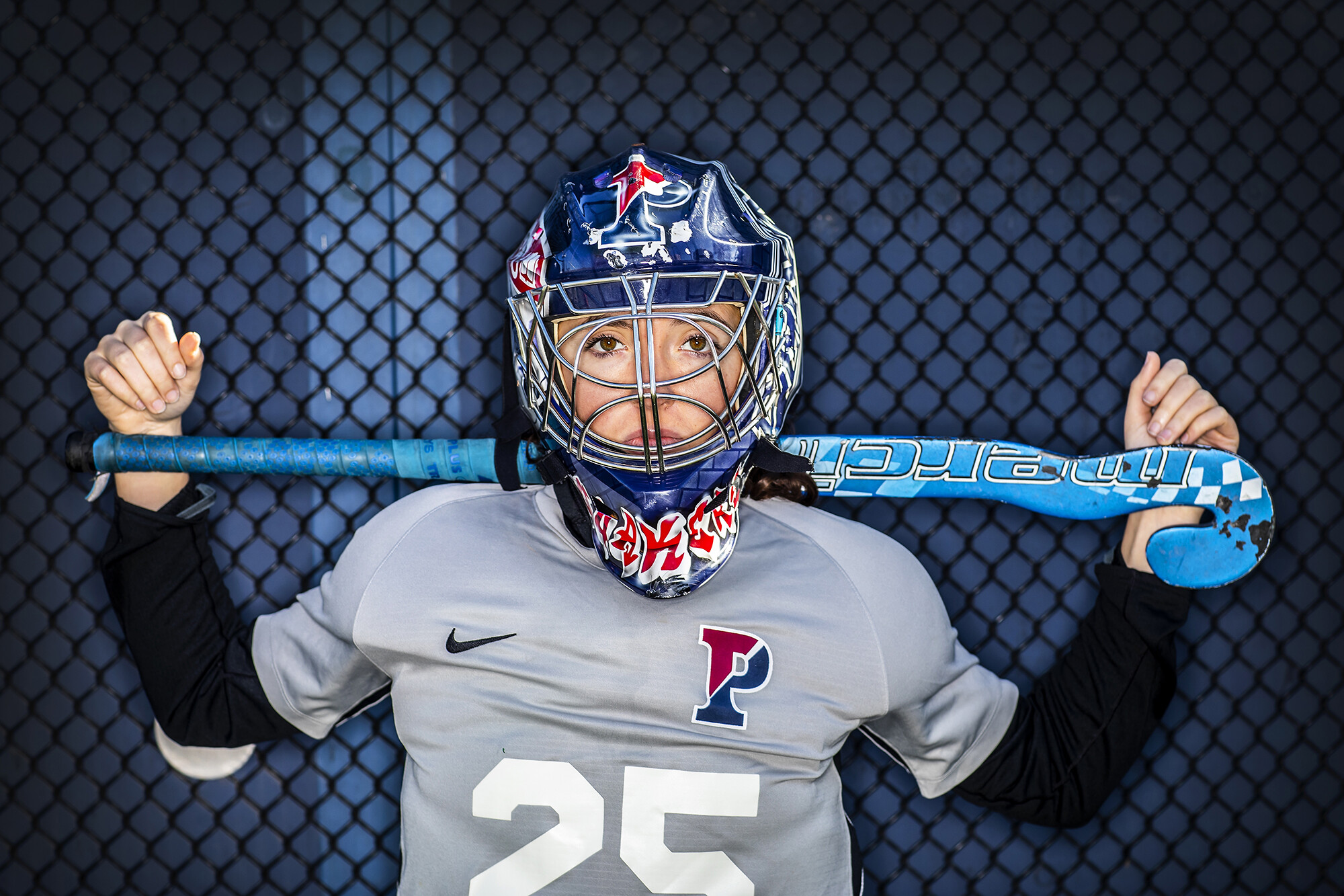 Wearing her goalie pads and helmet, Ava Rosati poses with her stick across her shoulders.