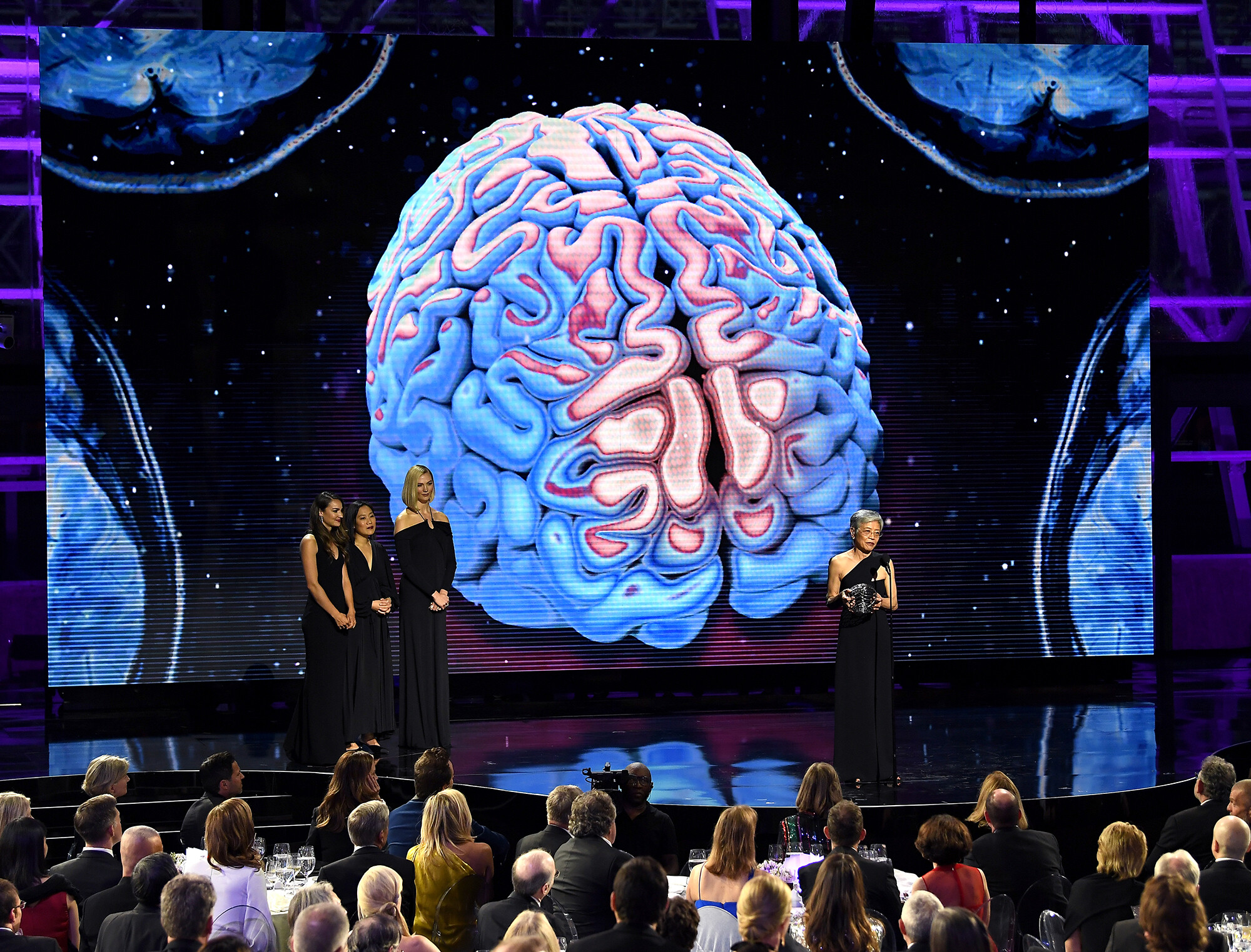 Virginia Lee accepts the Breakthrough Prize Award on stage and gives a speech, while the award presenter, Priscilla Chan, and Karlie Kloss look on from the stage