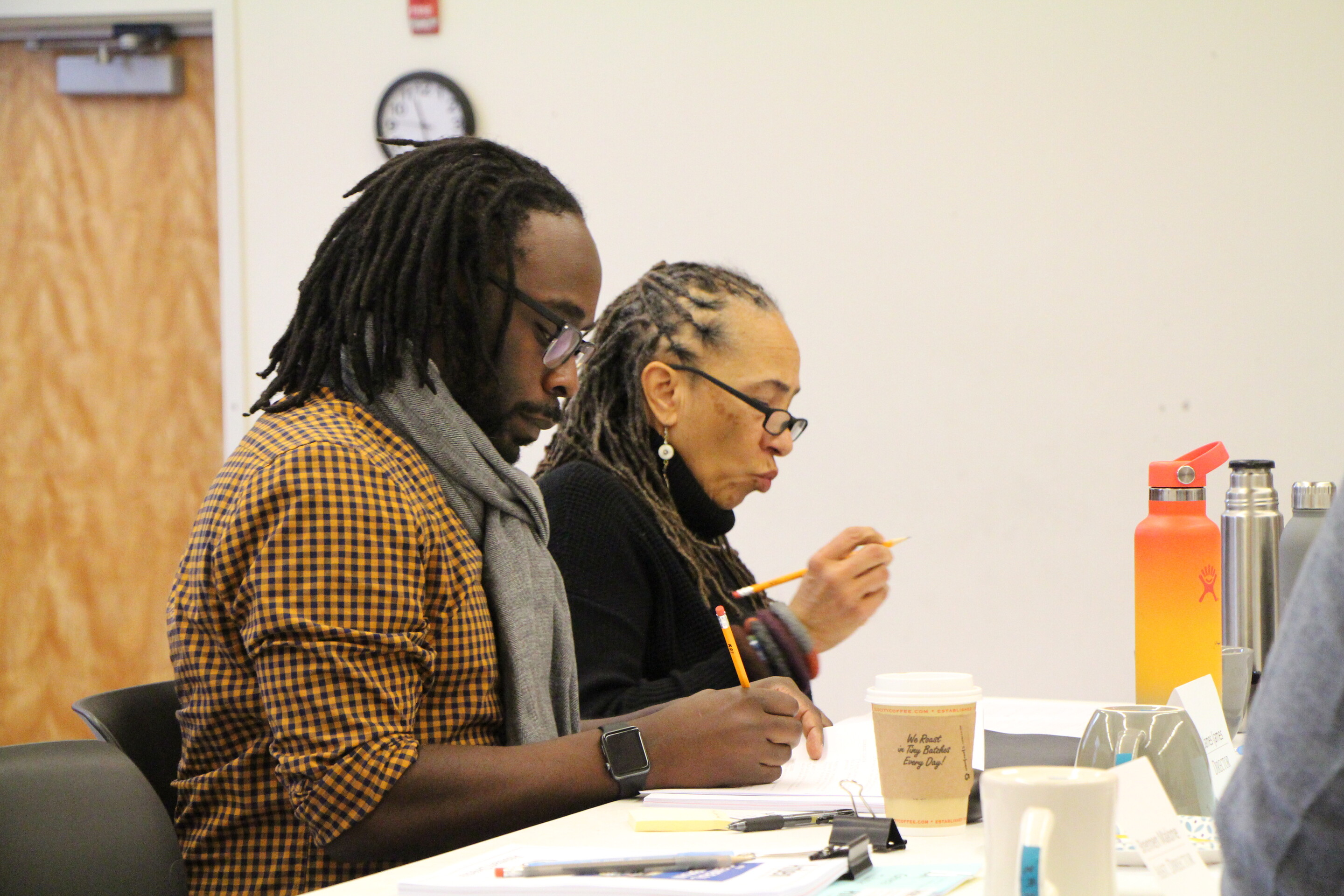 James IJames sits beside Lorene Cary at a desk, both working on screenplay notes