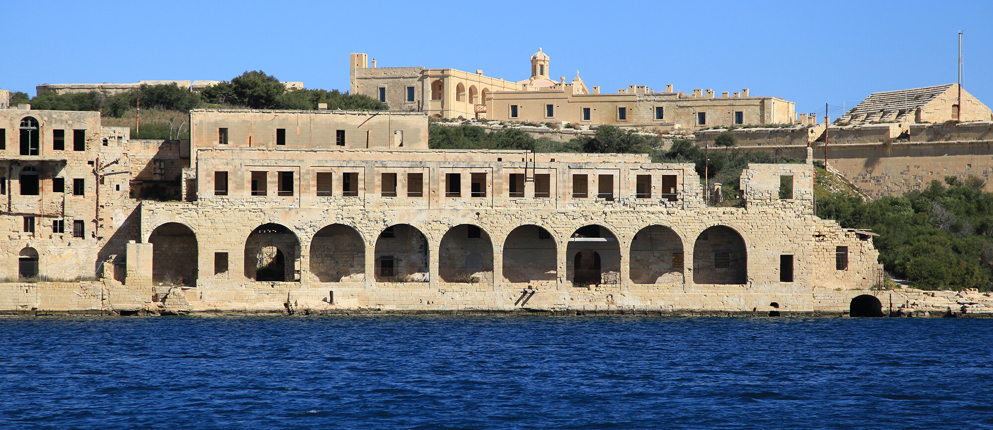 ancient stone building with archways along the ocean