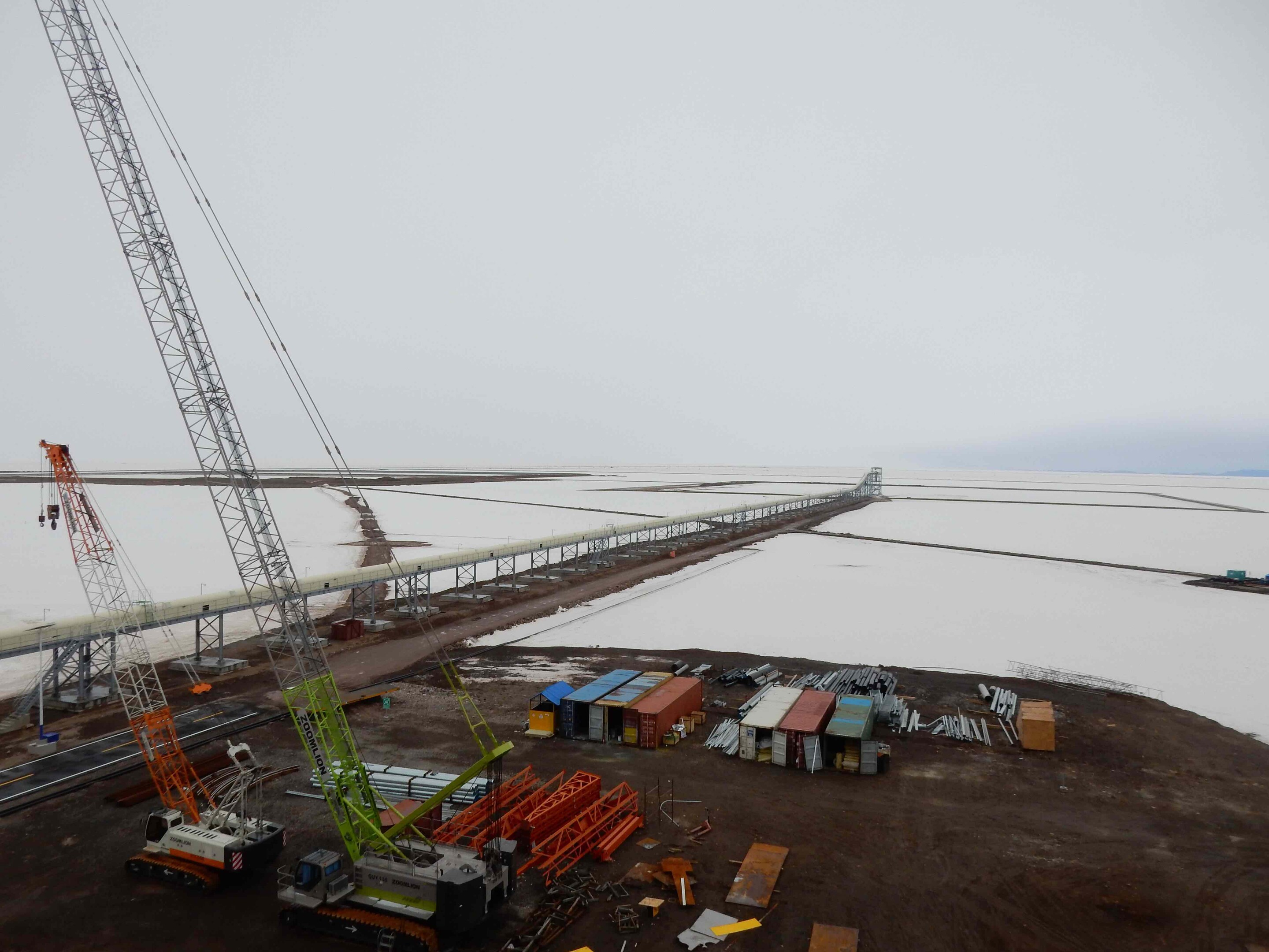 An industrial site with cranes stretches across a flat white surface