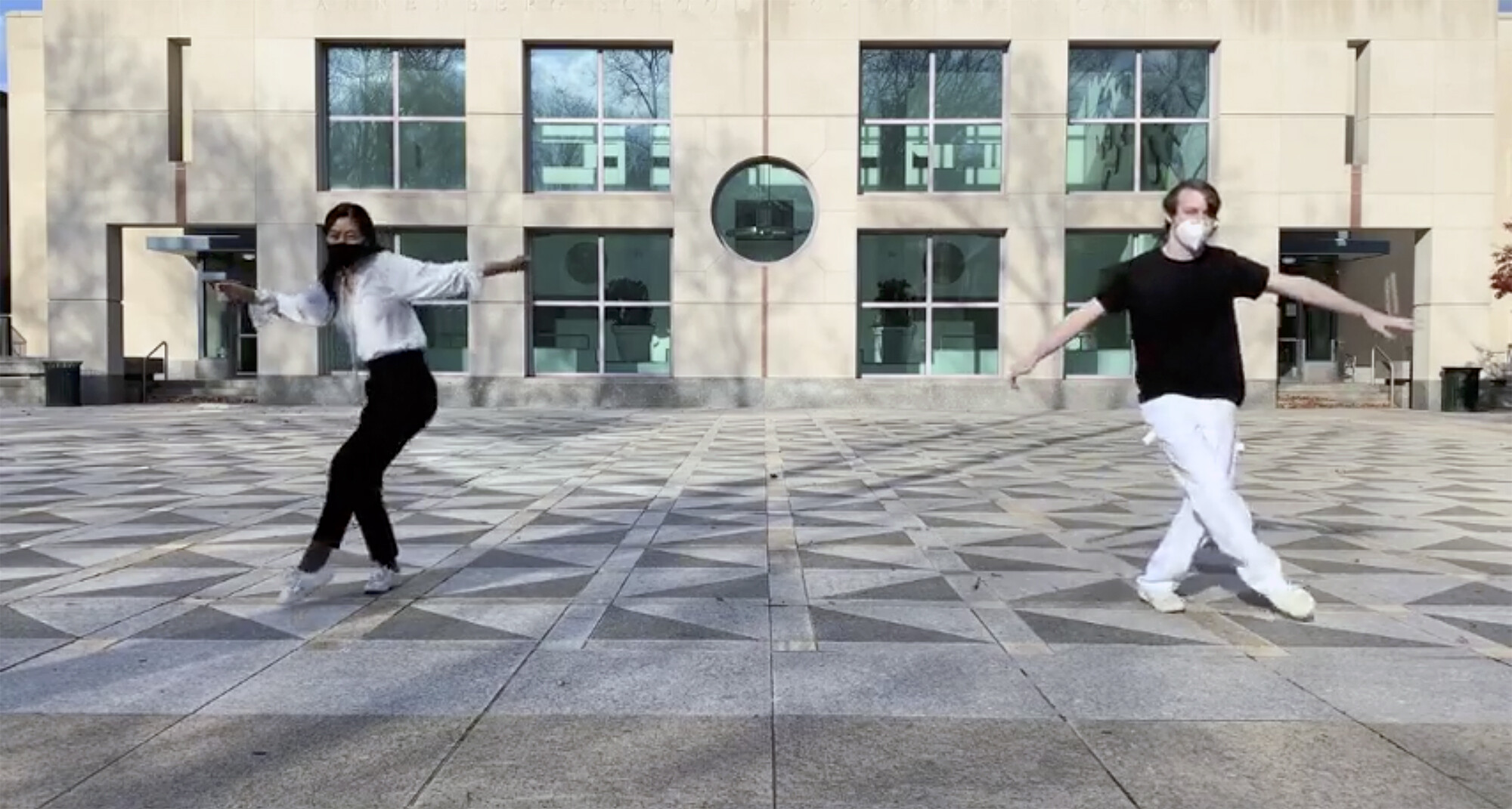 two students dancing outside in the Annenberg School building courtyard.