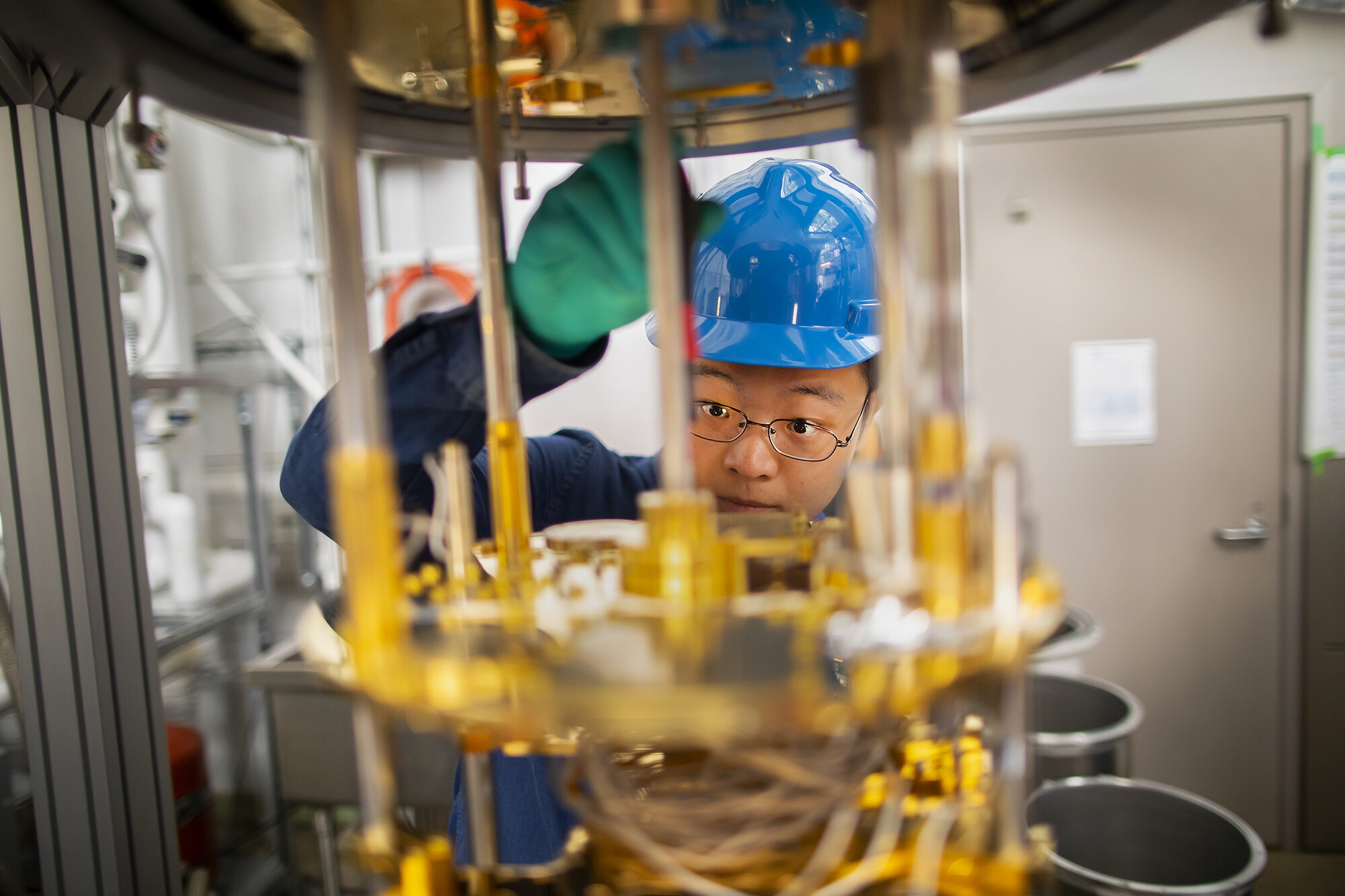 a person wearing a hardhat looking at an apparatus with wires and tubing