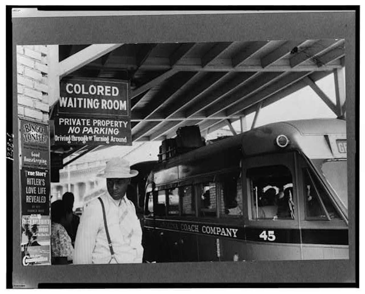 Man in hat and suspenders stands near a bus in Georgia in 1940