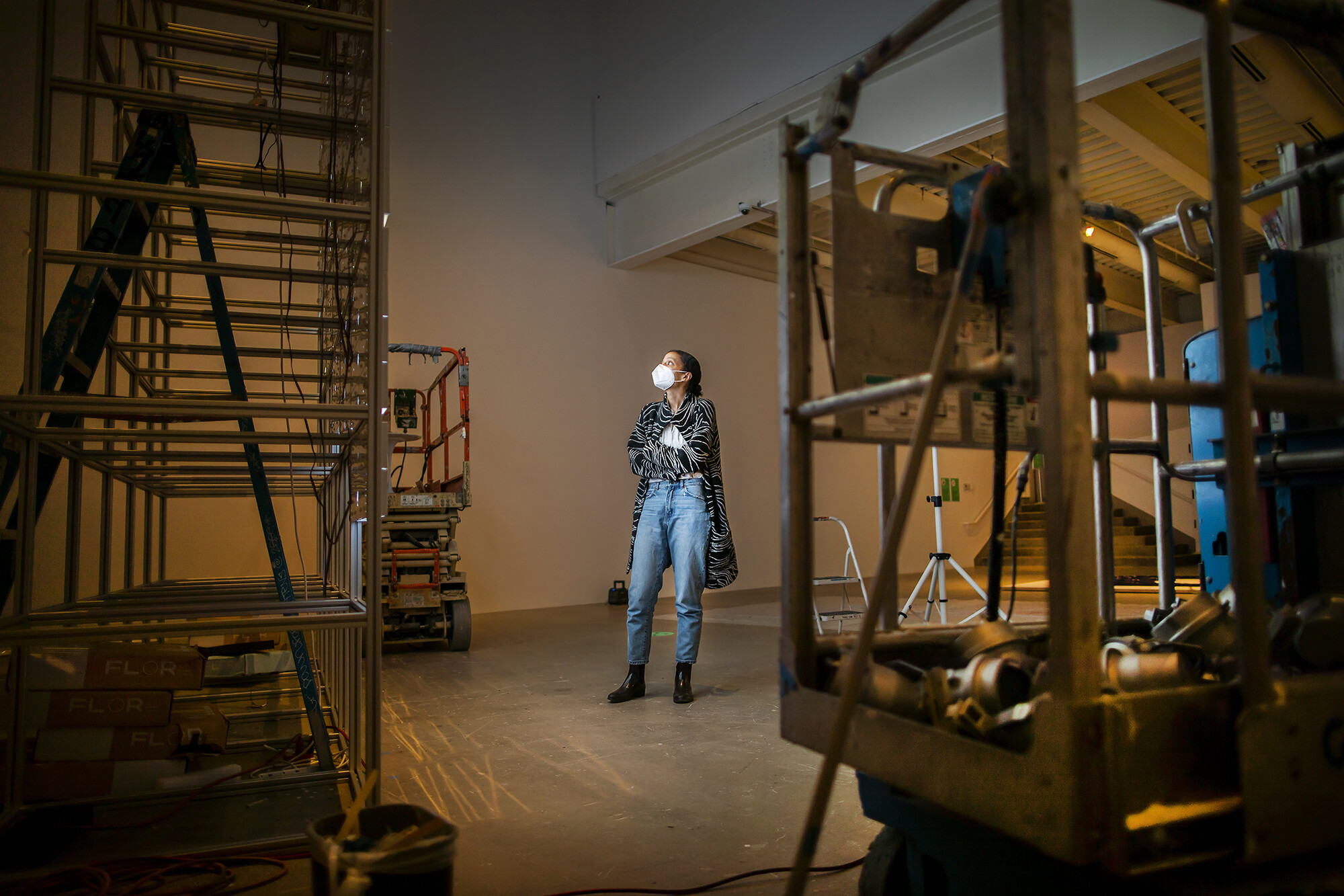 artist looking up at light installation surrounded by construction equipment 