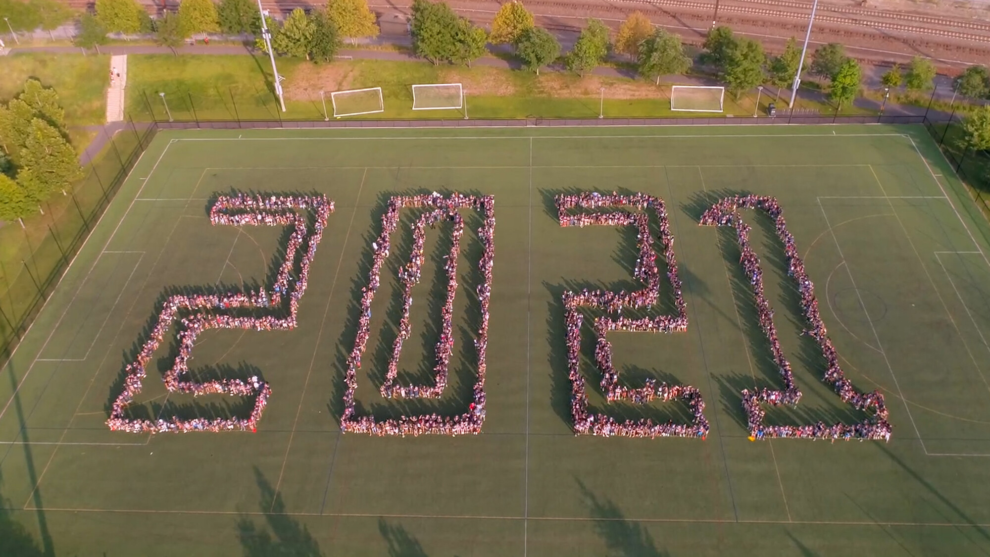 aerial view of people standing on field to spell out 2021