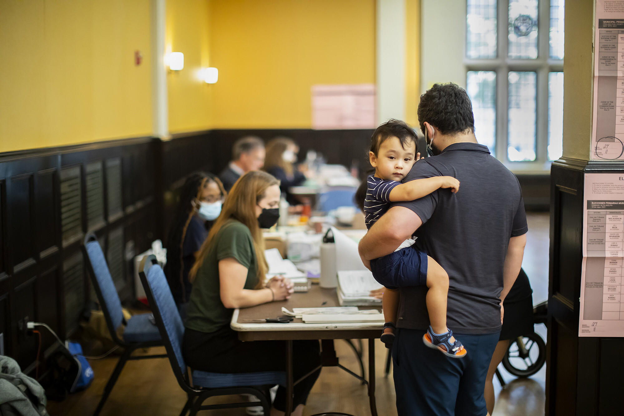 A parent holding a baby stands in line to vote at Houston Hall.