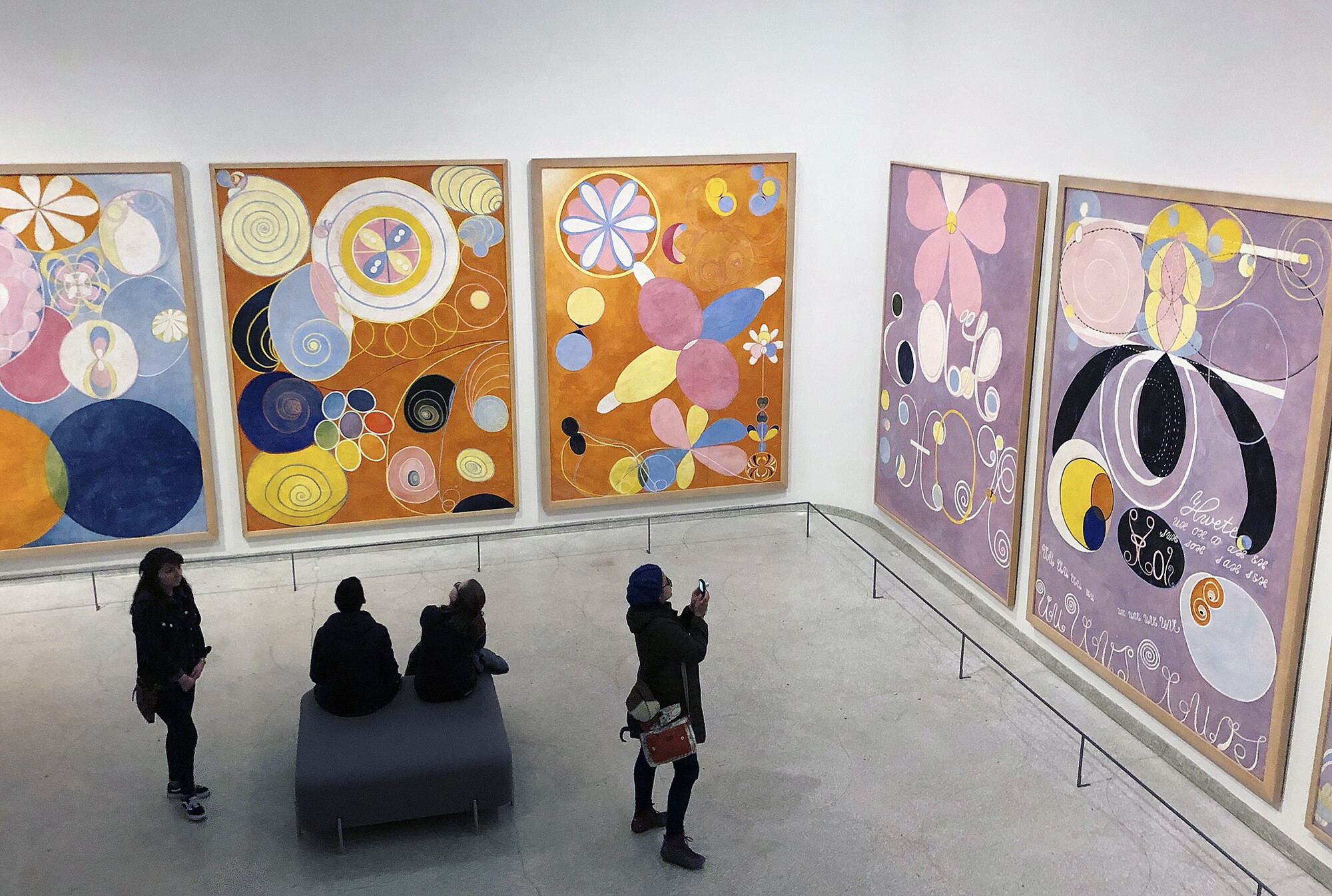 Image taken from above of people in an art museum taking photos and looking at large abstract paintings.