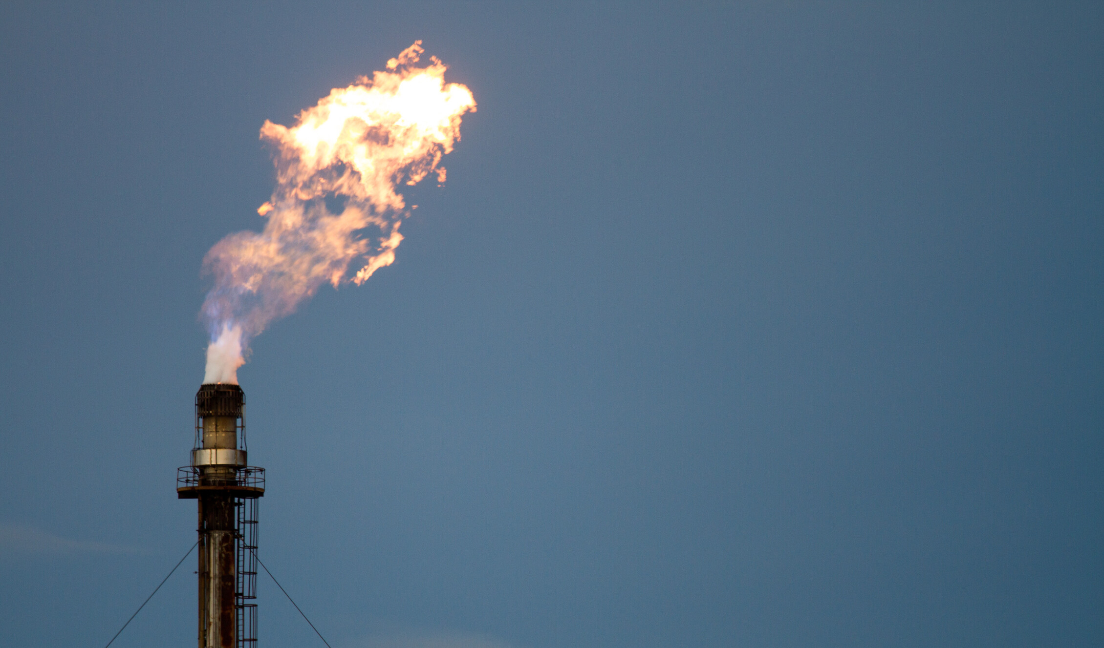 a methane flare against a blue sky