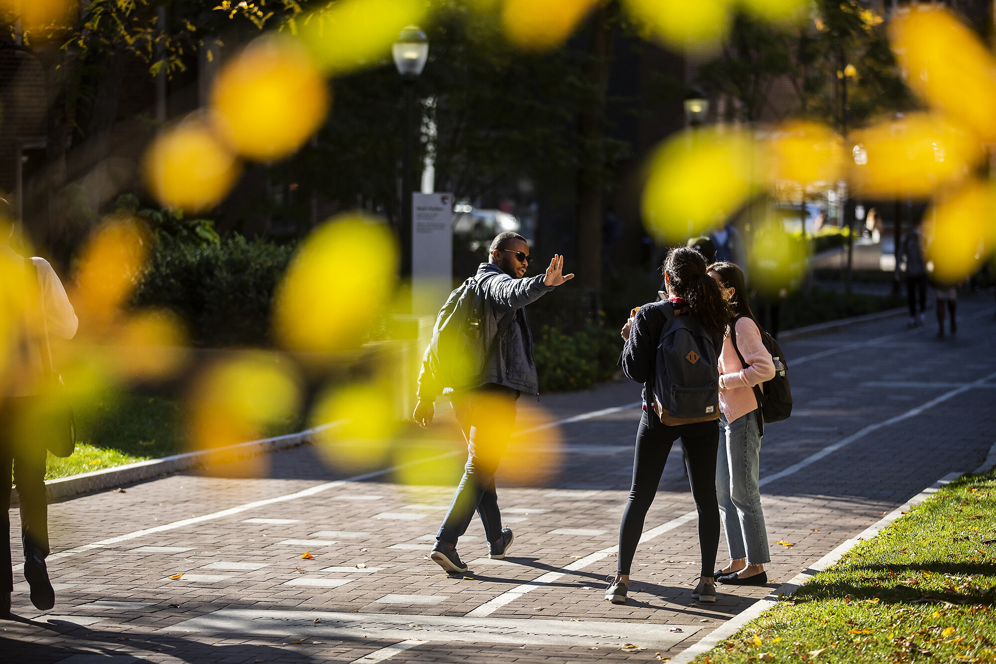 person on locust walk waves to two other people