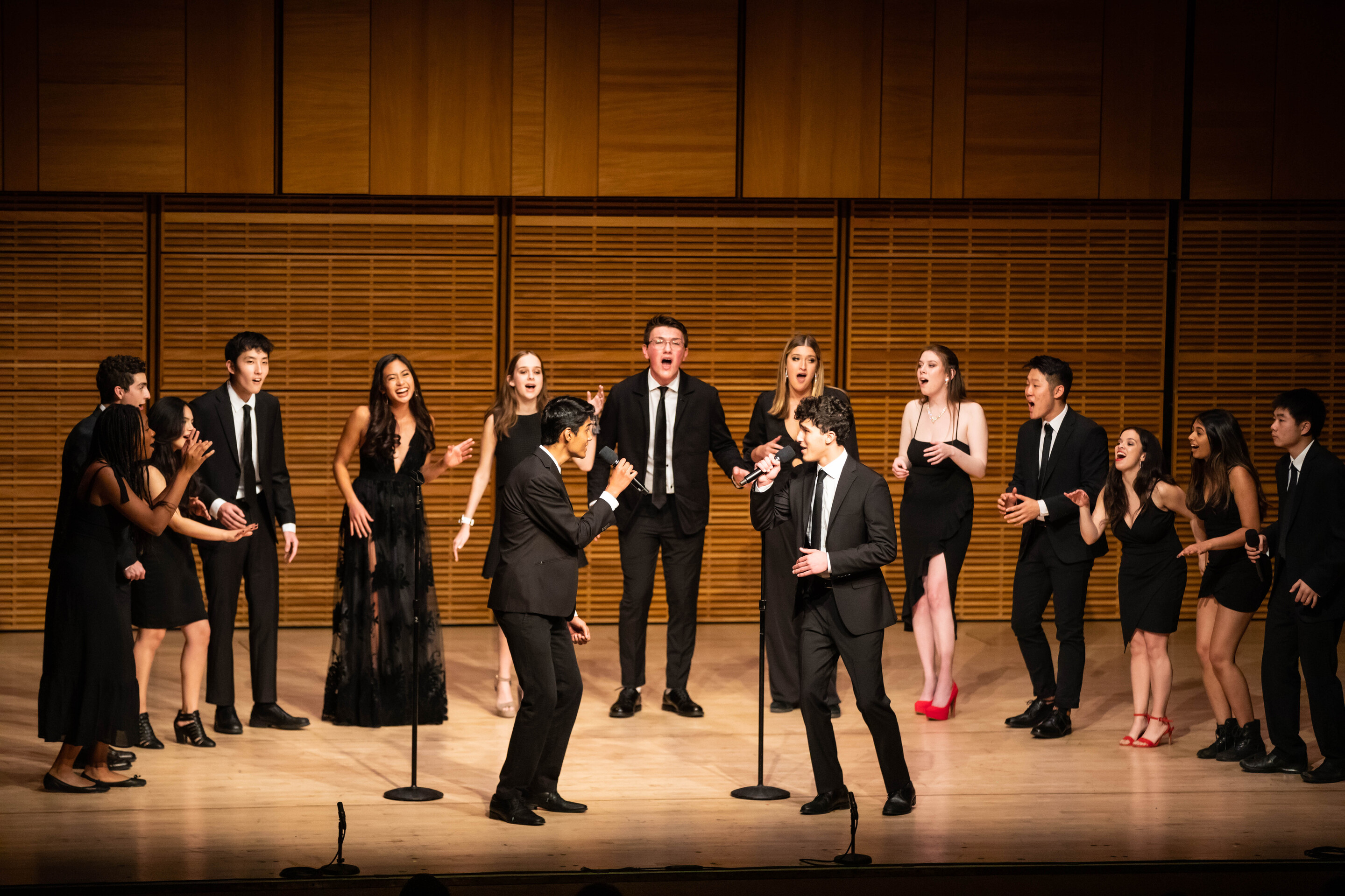 fifteen students singing on a stage