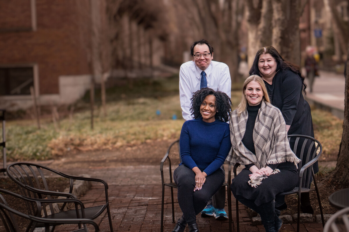 A group of four people outside--two in chairs, two standing