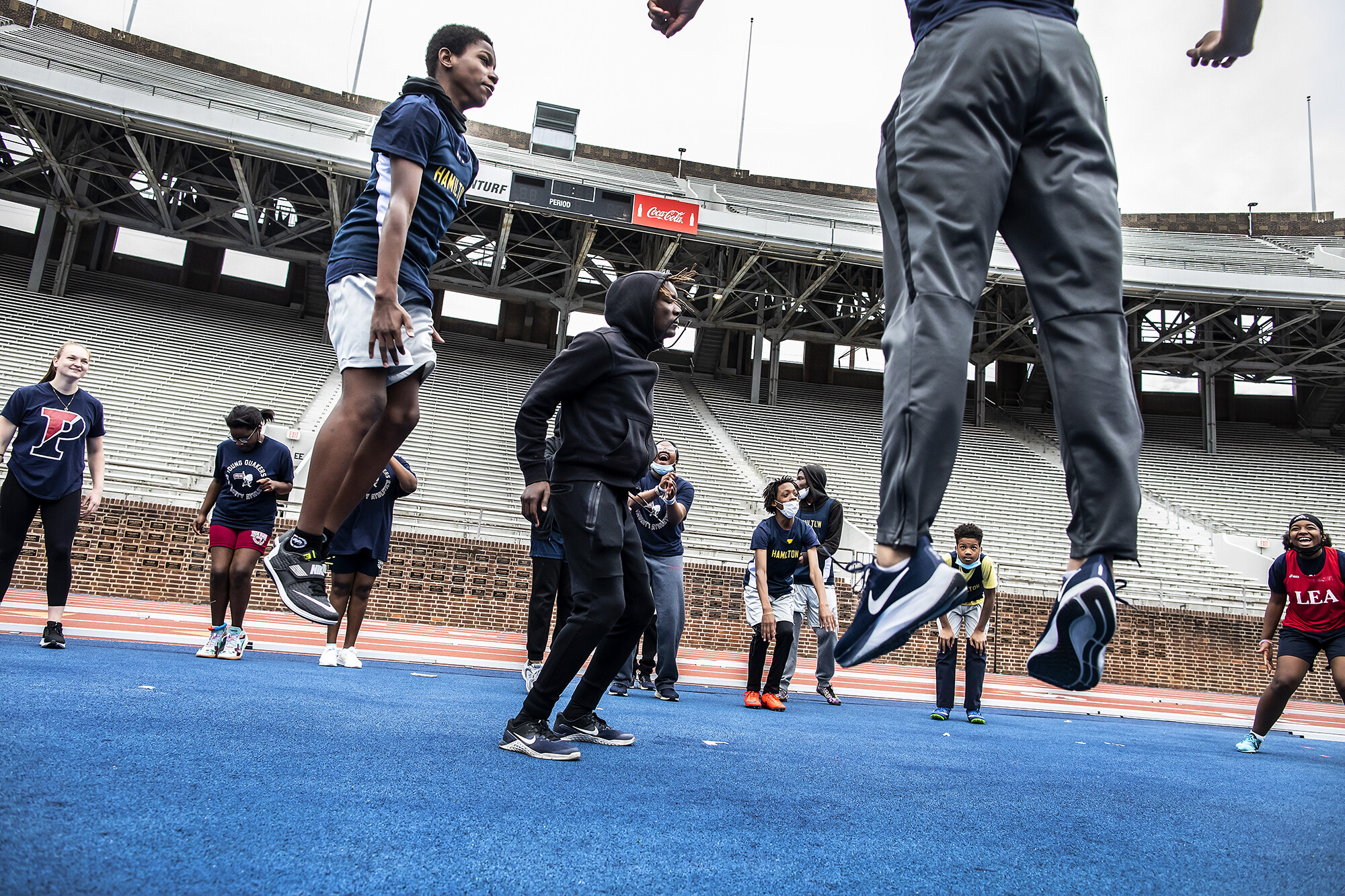 A group of middle school and college students jumping on a track