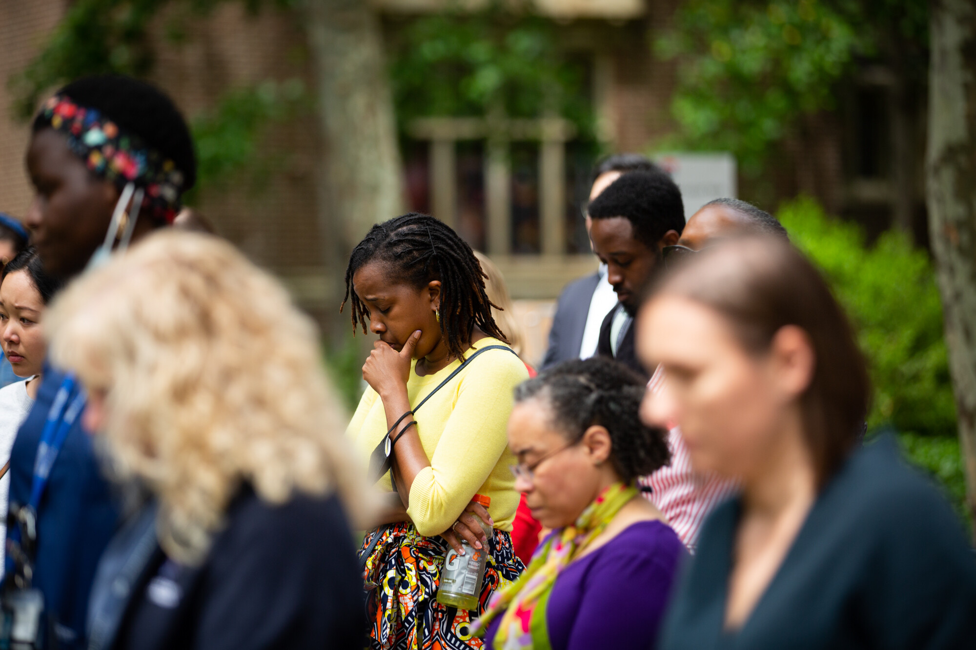 People in a crowd on College Green bowing their heads at Penn’s gun violence vigil.