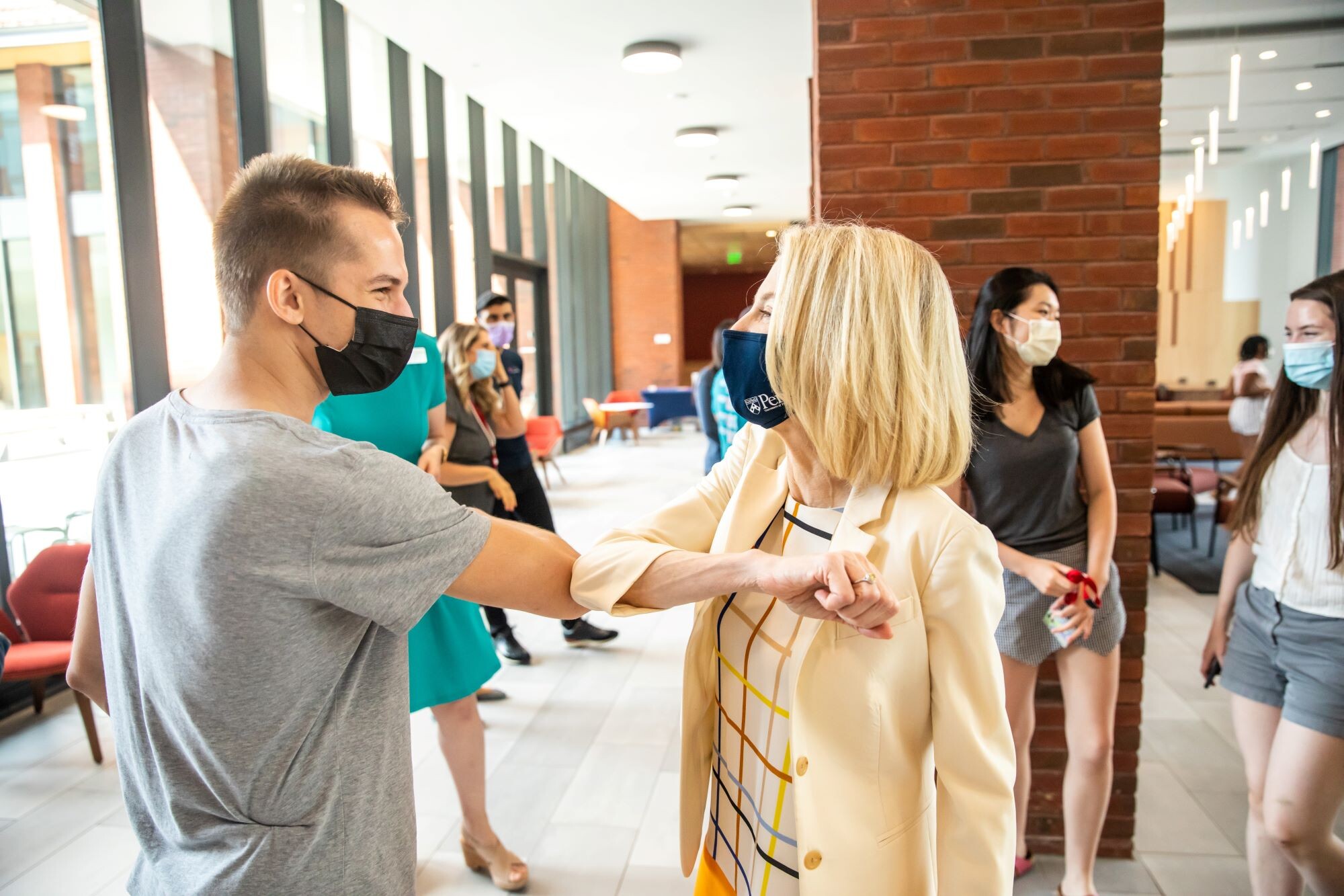 Amy Gutmann bumps elbows with a student at Gutmann College House.