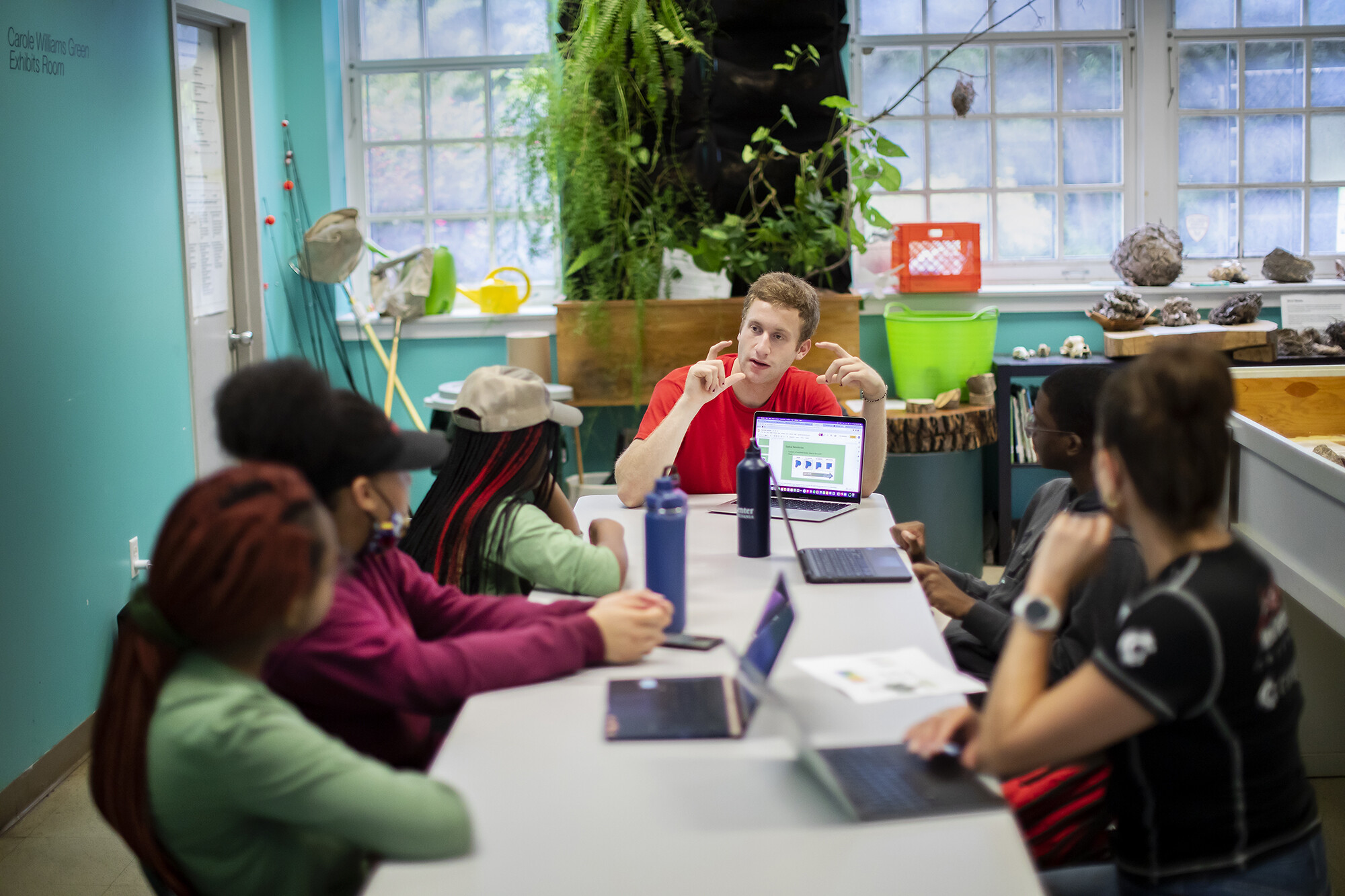 Henry Feldman at the head of a table with a laptop teaching five students.