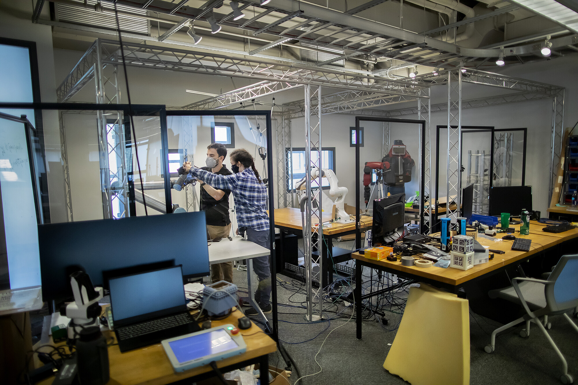 Two people wearing masks working on stickbot in a lab.