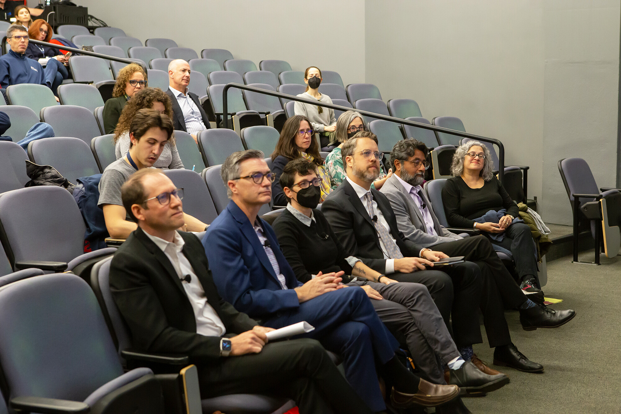 panelists sit in front row of auditorium