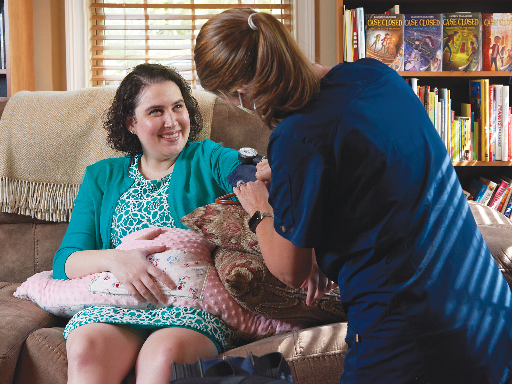 nurse taking blood pressure for patient at home
