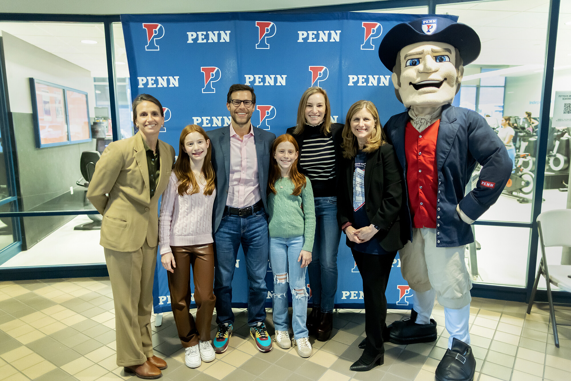 From left, Athletic Director Alanna Shanahan, Roxanne Goldman, alumnus Aaron Goldman, Harriet Goldman, alumna Stephanie Pottruck Goldman, President Liz Magill, and the Penn Quaker at the Pottruck Center birthday bash on Friday, Jan. 20. 