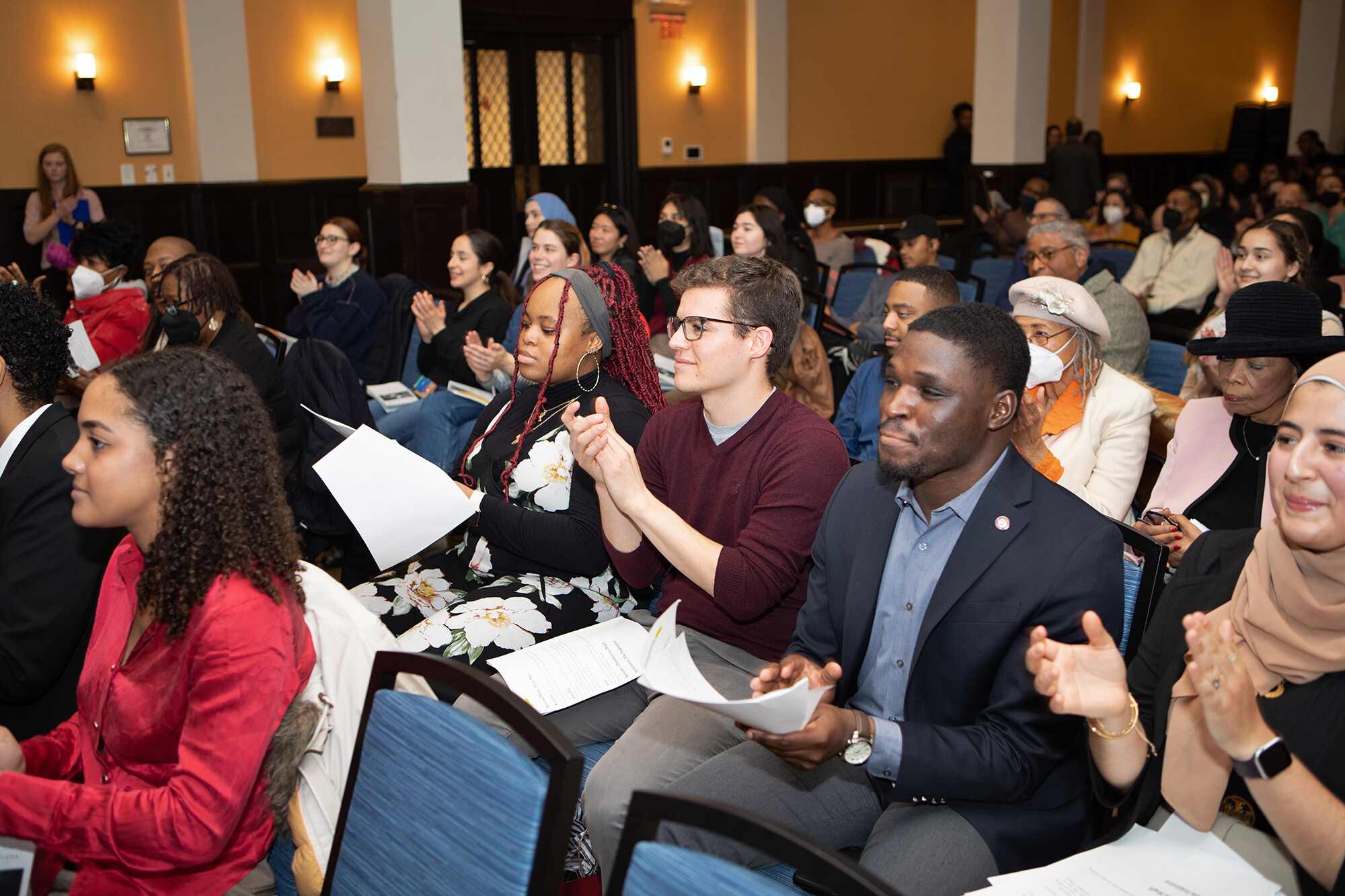 A crowd seated in Houston Hall applauds.
