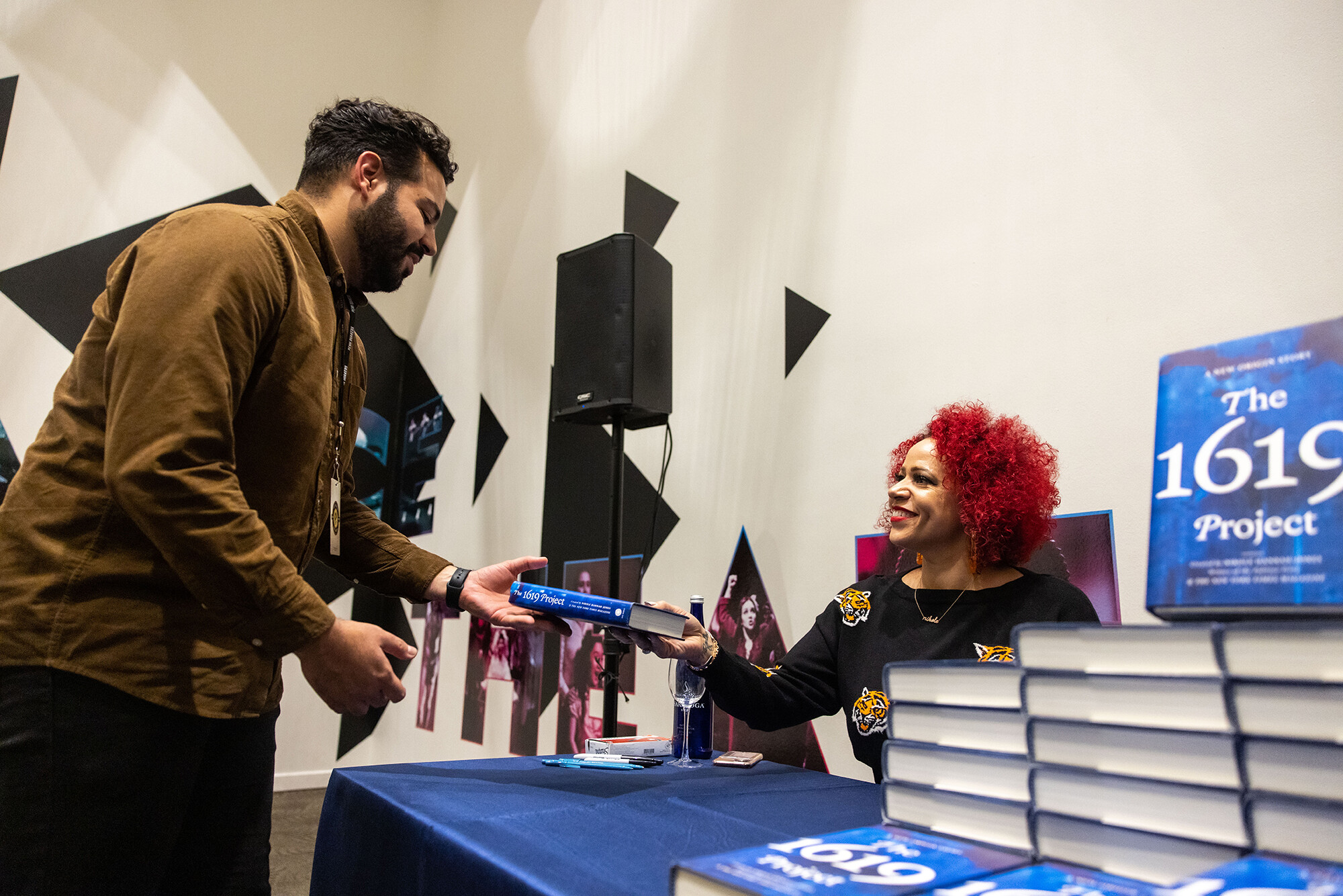Hannah-Jones hands a "The 1619 Project" book to a lecture attendee