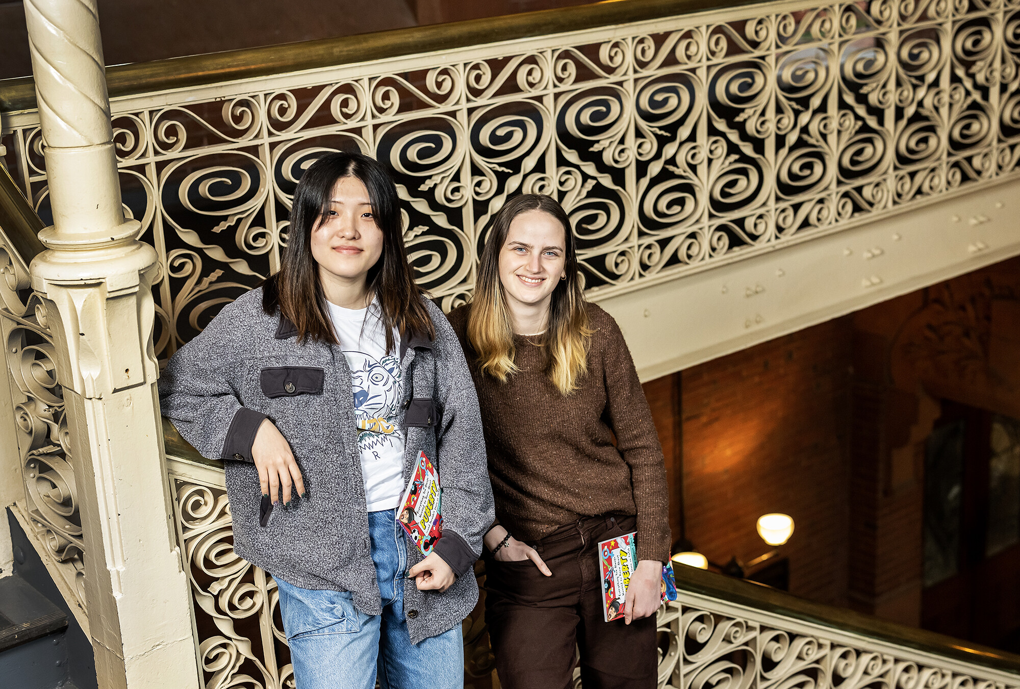 Gemma Hong and Sophie Young standing together holding copies of their book.
